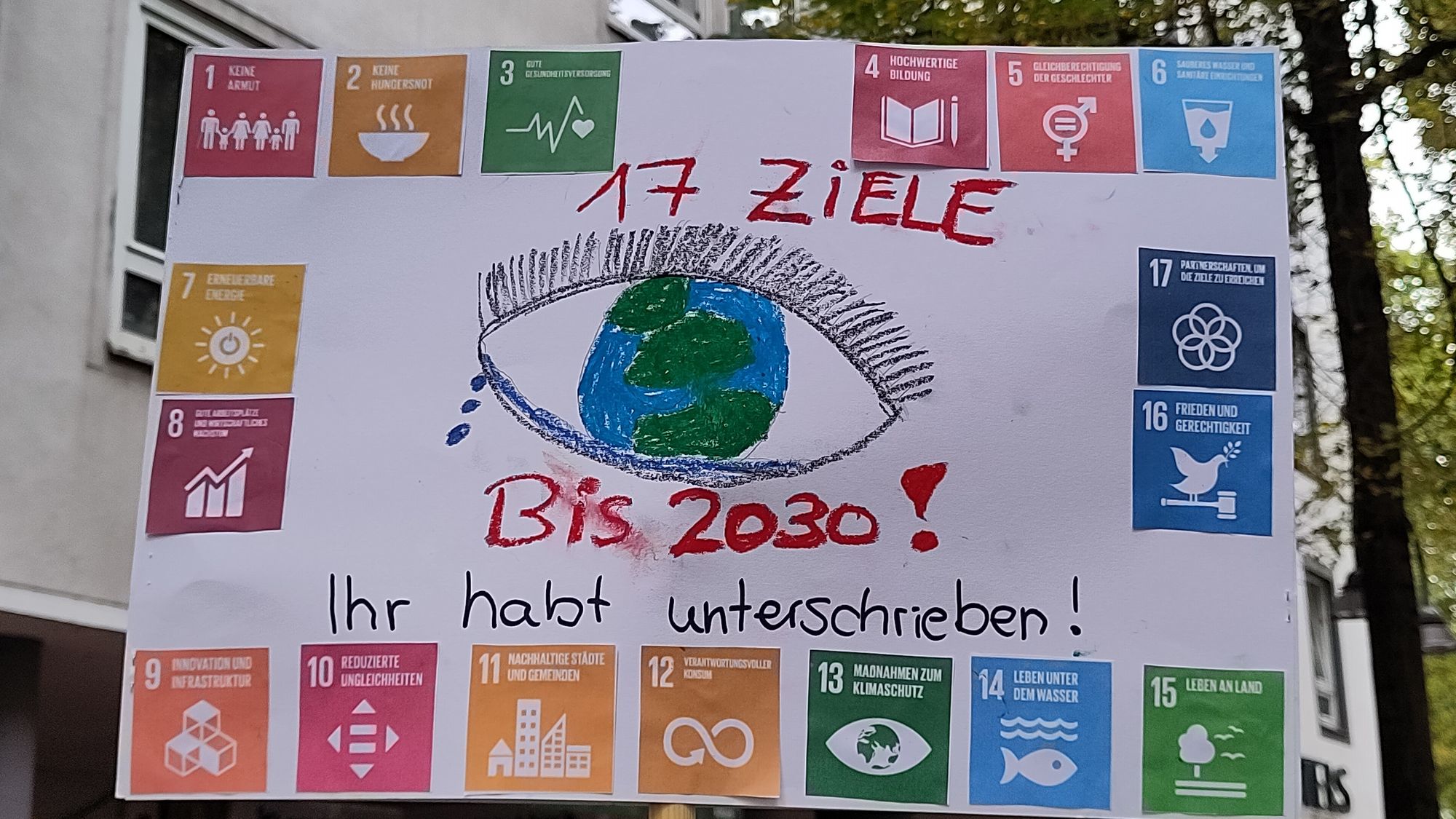 Ein Plakat, das über die 17 Nachhaltigkeits-Ziele der UN aufklärt. Textlicher Inhalt:

17 ZIELE Bis 2030!

Ihr habt unterschrieben!

1 KEINE ARMUT
2 KEINE HUNGERSNOT
3 GUTE GESUNDHEITSVERSORGUNG
4 HOCHWERTIGE BILDUNG
5 GLEICHBERECHTIGUNG DER GESCHLECHTER
6 SAURERES WASSER IND SANITÄRE EINRICHTUNGEN
7 ERNEUERBARE ENERGIE
8 GUTE ARBEITSPLÄTZE UND WIRTSCHAFTSWACHSTUM
9 INNOVATION UND INFRASTRUKTUR
10 REDUZIERTE UNGLEICHHEITEN
11 NACHHALTIGE STÄDTE UND GEMEINDEN
12 VERANTWORTUNGSVOLLER KONSUM
13 MAẞNAHMEN ZUM KLIMASCHUTZ
14 LEBEN UNTER DEM WASSER
15 LEBEN AN LAND
16 FRIEDEN UND GERECHTIGKEIT
17 PARTNERSCHAFTEN, UM DIE ZIELE ZU ERREICHEN