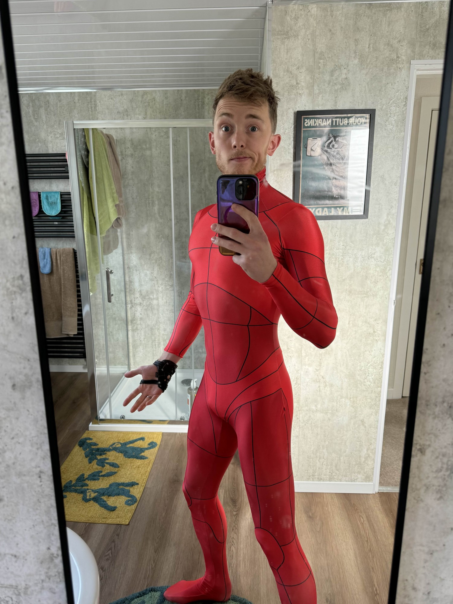 A man taking a photo of himself wearing a red suit with isolated body parts drawn on it.