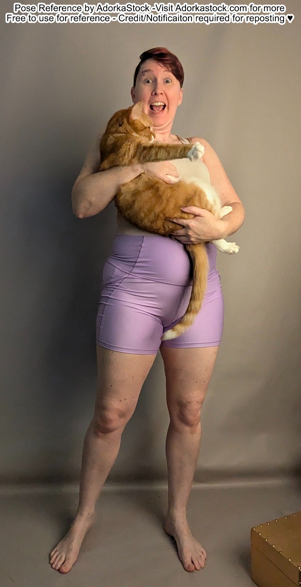 thin white female pose reference model holding a squirming orange and white cat