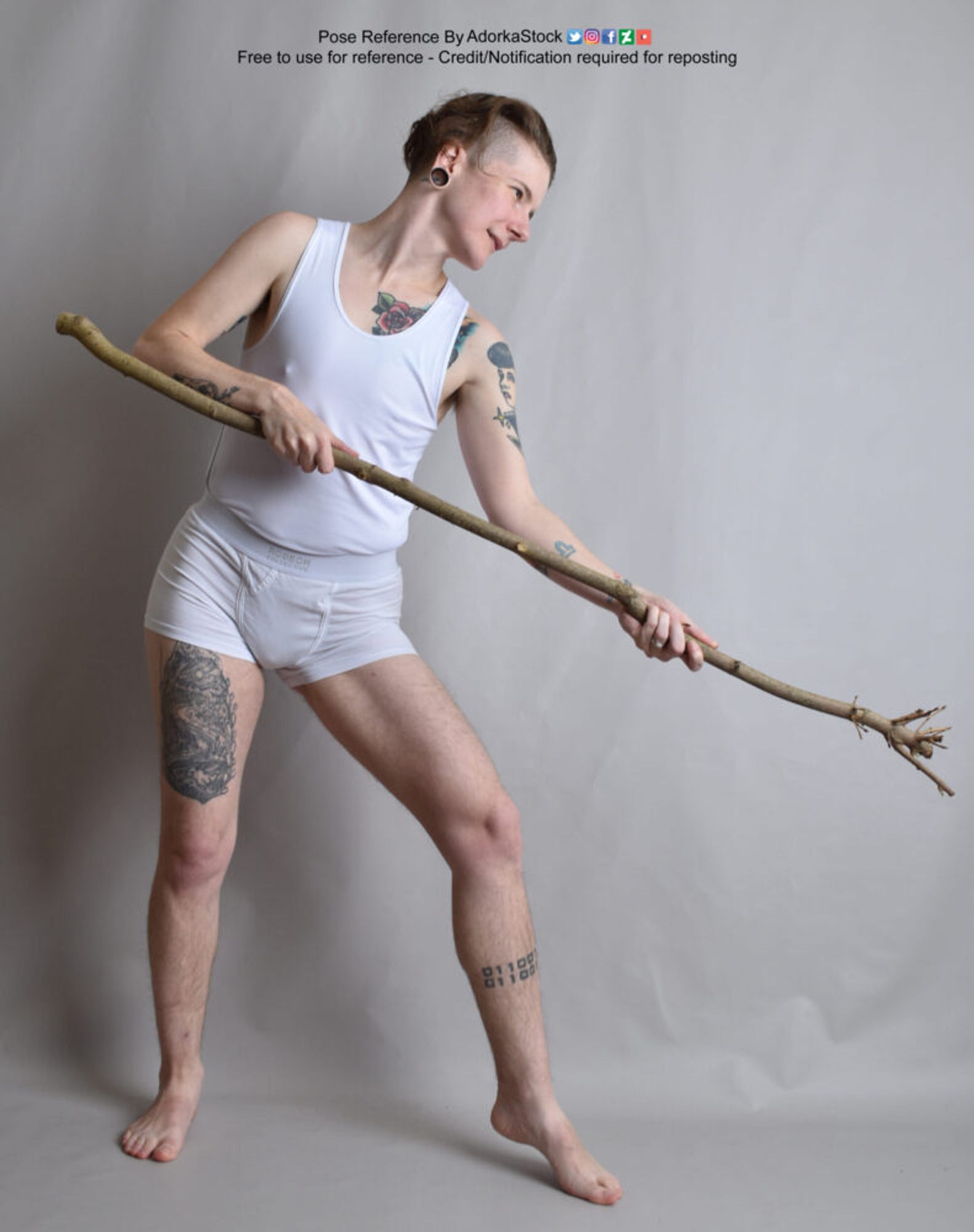 Thin, nonbinary, white pose reference model standing with a stick pointed sort of down, face in profile as if casting a spell.