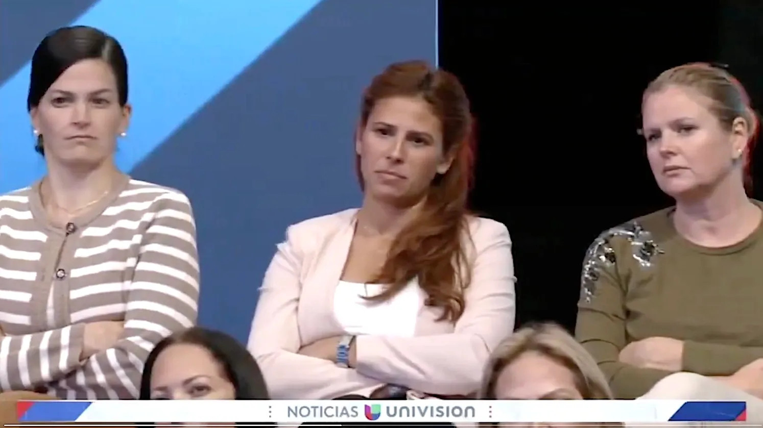 Three women, scowling, listening to Donald Trump with their arms folded. They know he's all up on his bullshit.