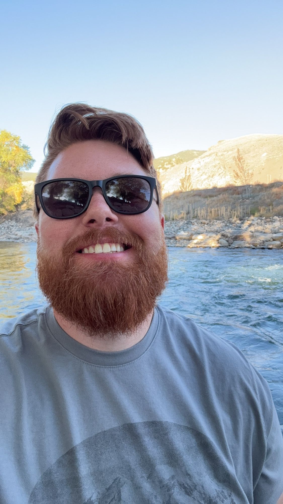 Ginger cub smiling in front of a river.