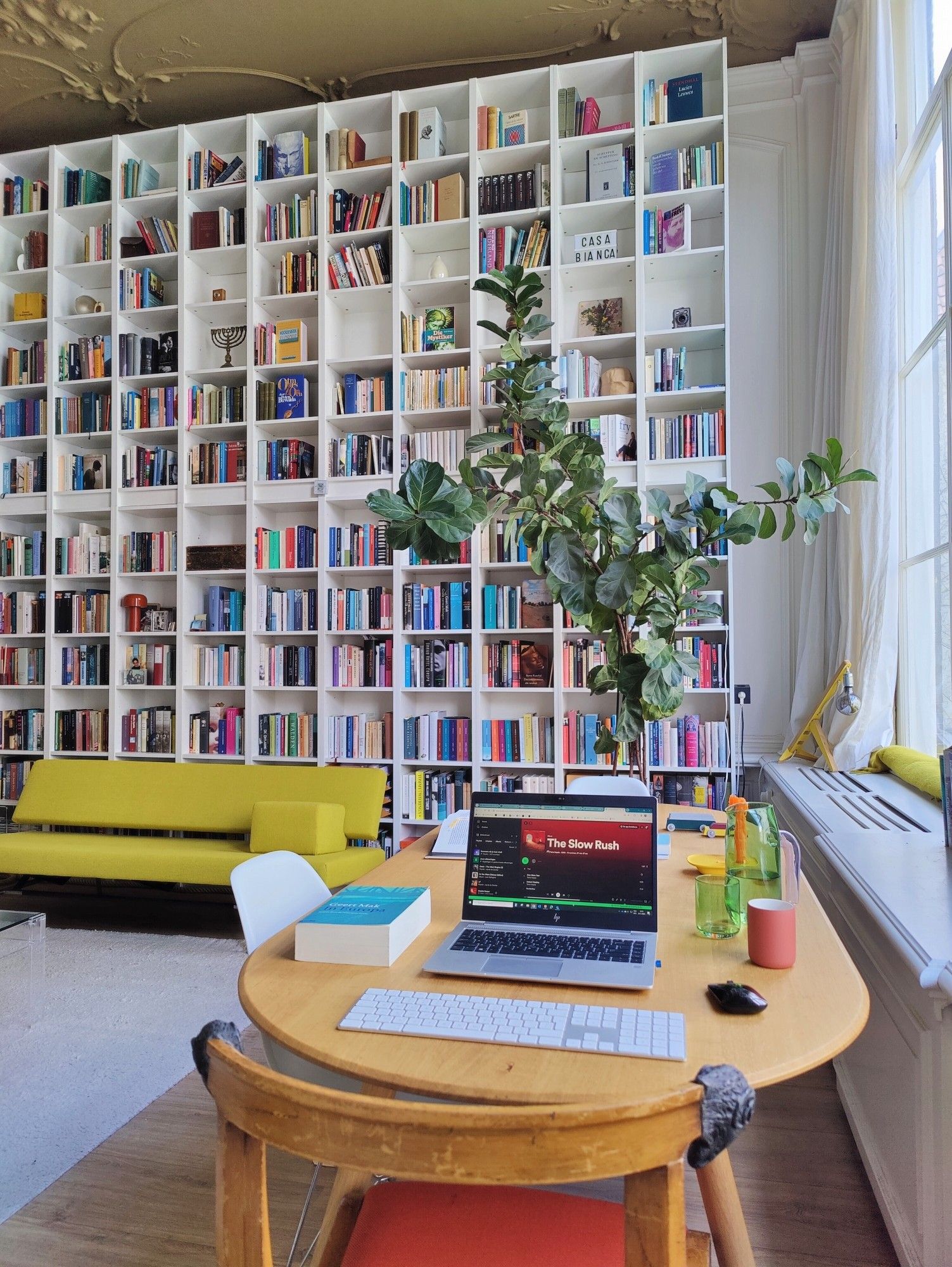 De mooie huiskamer van mijn moeder in Amsterdam met haar prachtige designmeubels en -spullen en tegen de wand haar enorme boekenwand bestaande uit 34 op elkaar gestapelde Billy-boekenkasten.