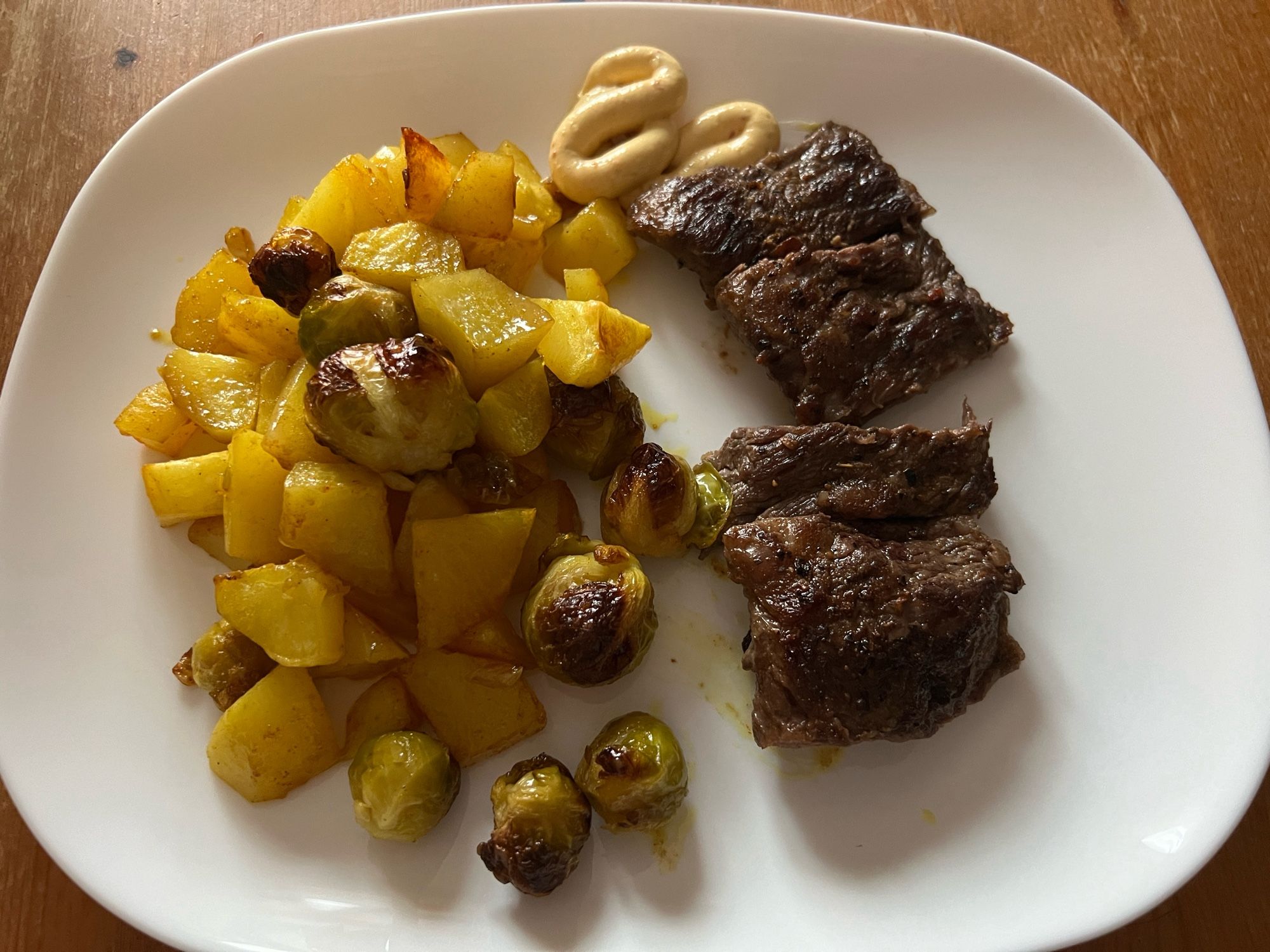 Weißer Teller mit Wagyusteak und Kartoffeln und Rosenkohl aus dem Backofen