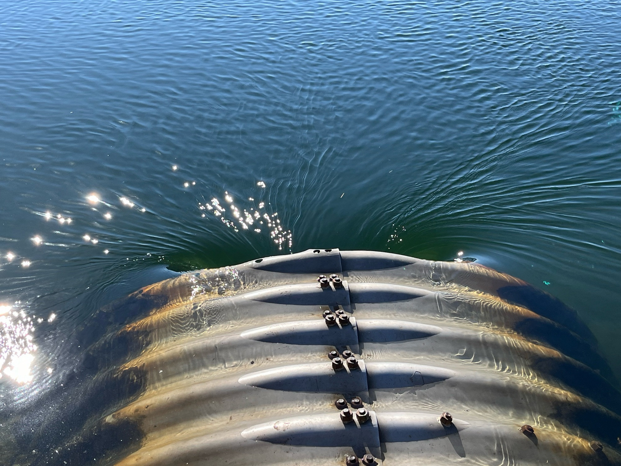 Corrugated metal pipe in lower section of image with water around draining into pipe opening near middle of image. Only the very top of pipe is dry.