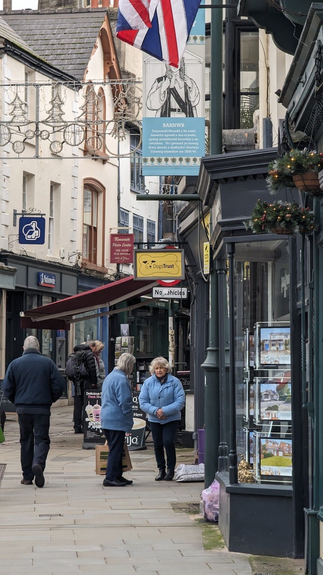 Typical street scene in Monmouth as people go about their business. Two elderly women in blue jackets stop and chat.