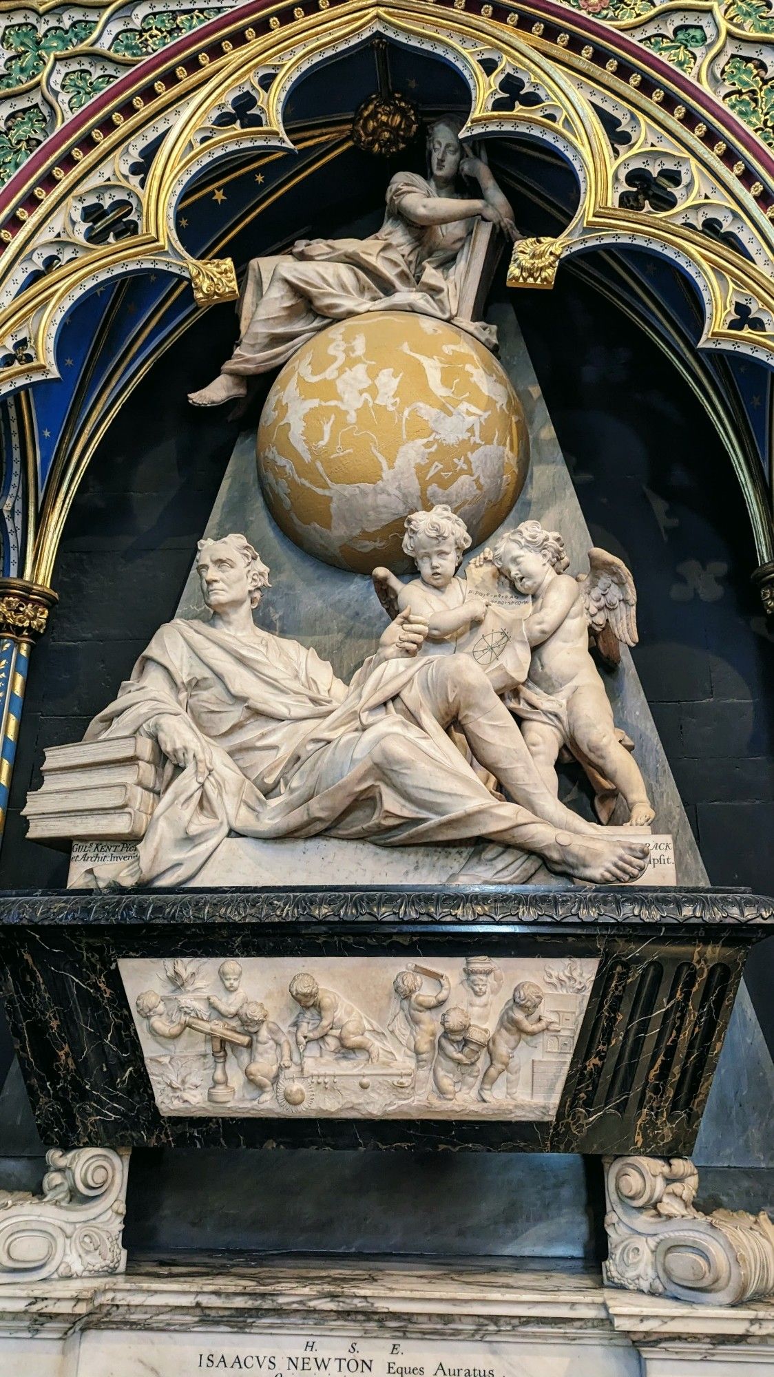 Large alcove with a statue of Sir Isaac Newton draped in robes over books. Cherubs float around with various science malarkey, the heavens as a globe is above.