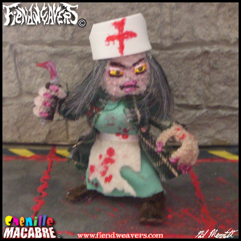 A pipe cleaner figure I built of Nurse Toddle, a playable character in my tabletop fighting game AMPUTHEATRE. Nurse Toddle is diminutive woman in her late 50's with grey shoulder length hair, pale acne covered skin, a flannel shawl over surgical scrubs, and a bloody linoleum knife. Her head and arms are removable for AMPUTHEATRE gameplay.