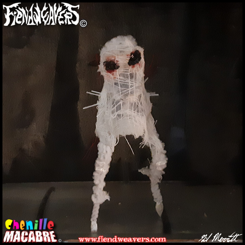 A pipe cleaner figure I built of the Fresno Nightcrawler. It is a white, amorphous biped with black eyes and two spindly legs. Bristles appear where its arms should be.