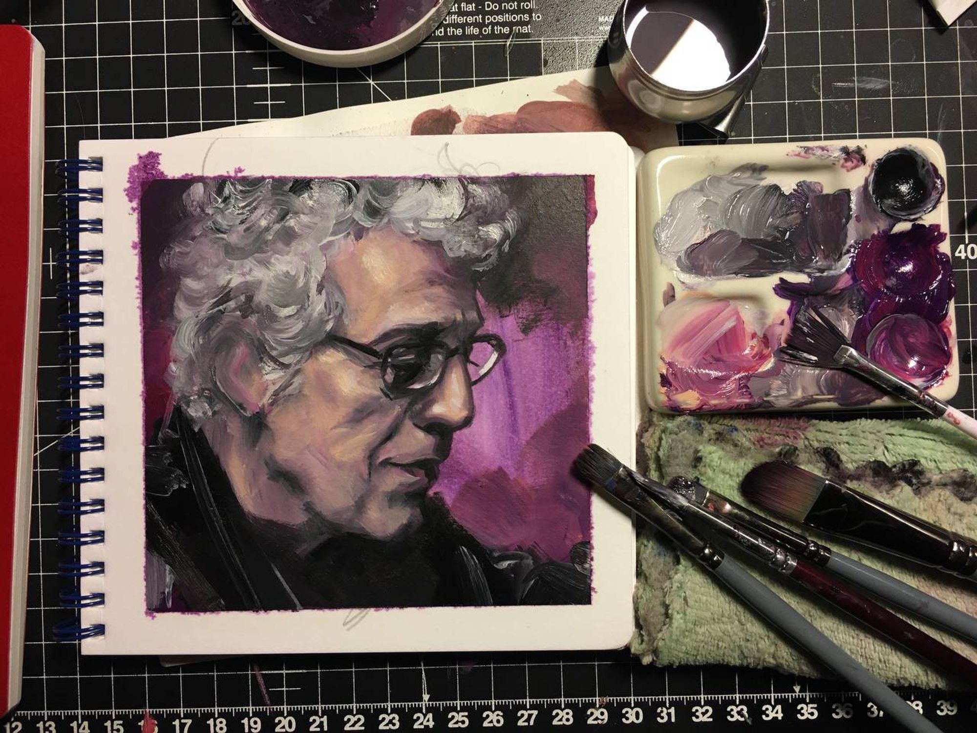 The same picture of a small oil painting of Eric Bogosian, but shot at a better angle with paints and brushes still visible in the frame.