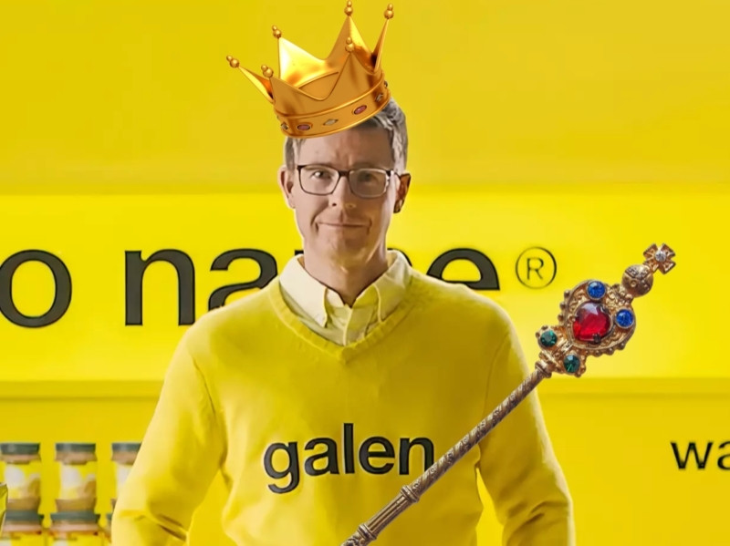 Galen weston jr. with a septer and crown dressed in yellow of the no name brand