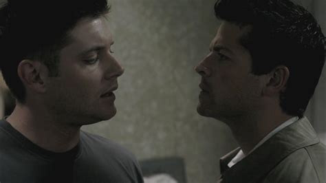 Dean and Castiel standing close to each other. Castiel is frowning, Dean is looking at Castiel's lips.