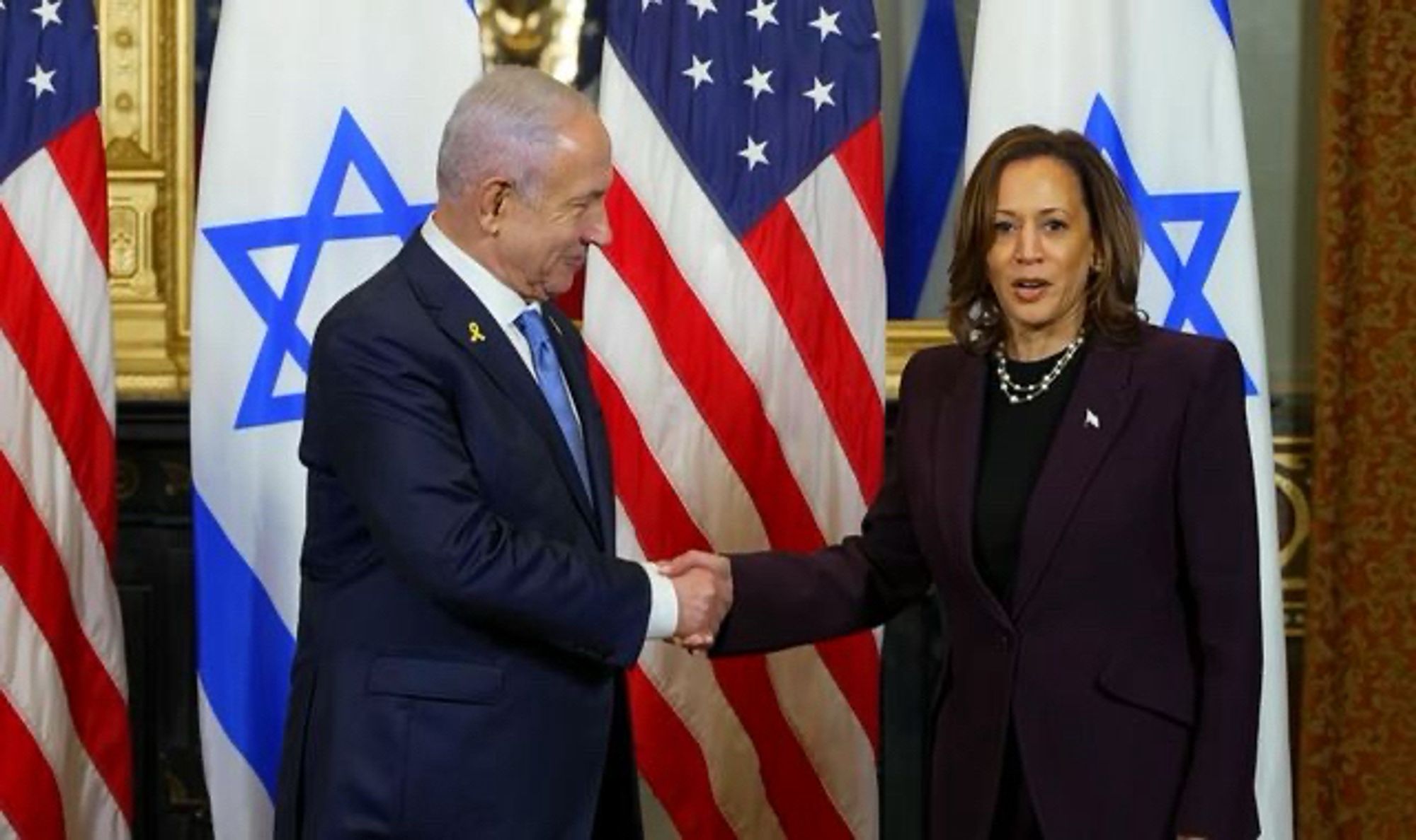 Kamala Harris shaking Netanyahu’s hand with USA and Israeli flags in the background.