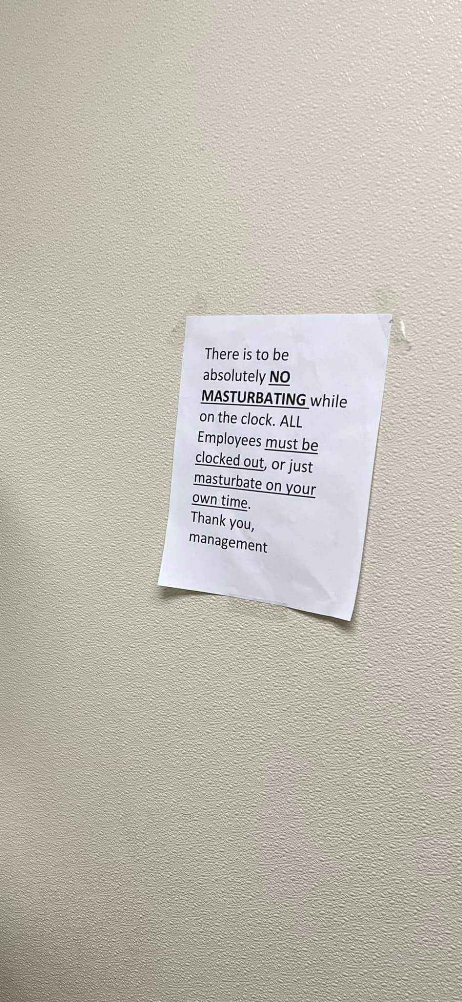 Paper sign taped to a wall reads "There is to be absolutely no masturbating while on the clock. All employees must be clocked out, or just masturbate on your own time. Thank you, management"