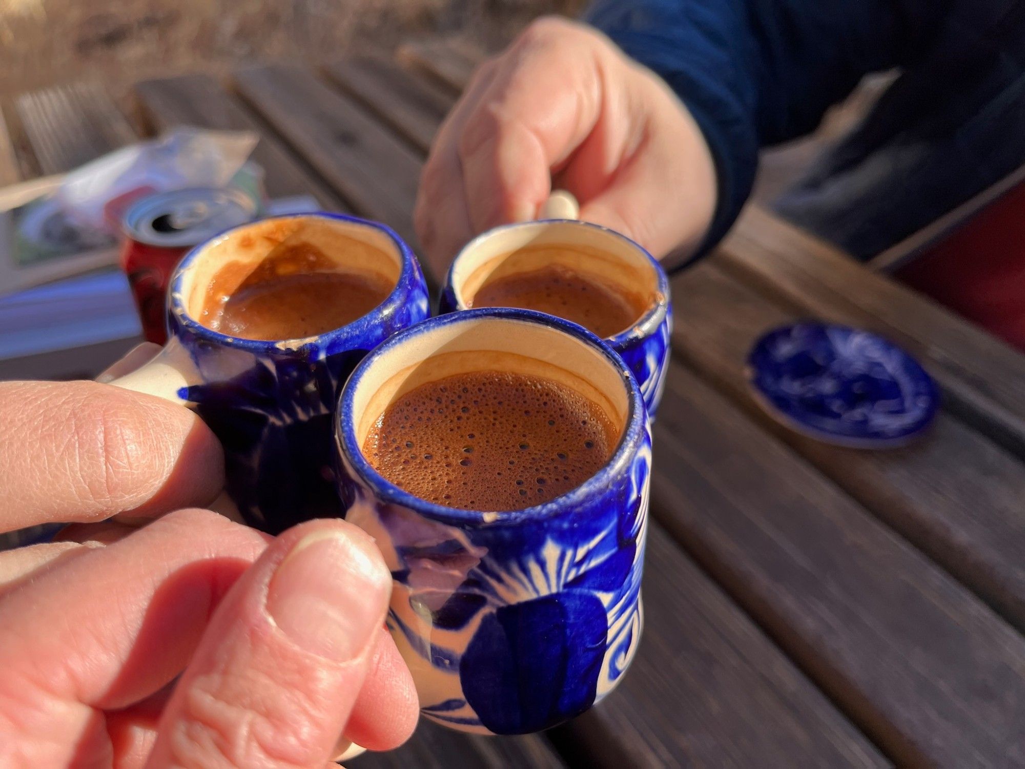 Three drinking chocolates are being cheersed in tiny 3oz ceramic mugs with striking messo american blue and white designs painted on them.