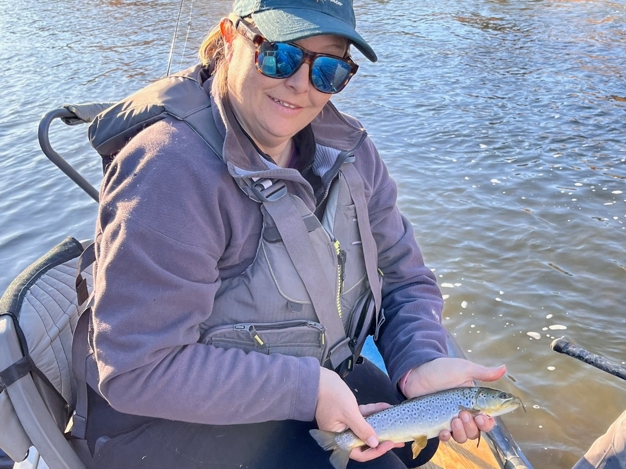 Me, holding a 10inch brown trout in breeding colors that i caught on a fish egg fly. I'm sitting in a the front of a raft with the sun glistening on the rio grande making it look much warmer than it was.