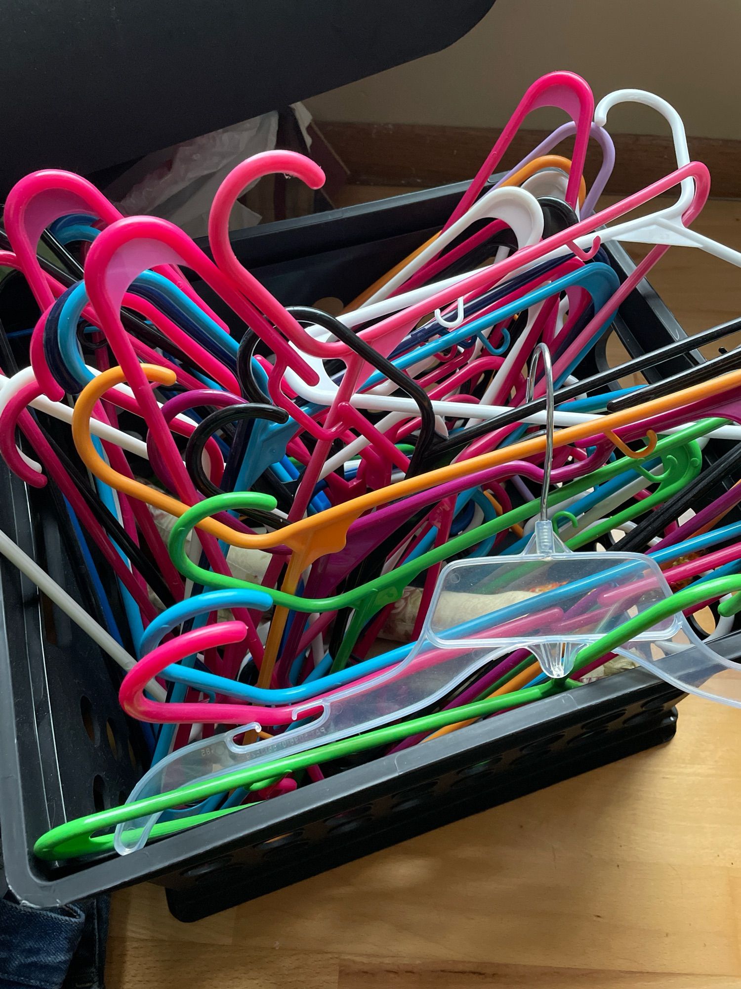 A plastic milk crate full of hangers