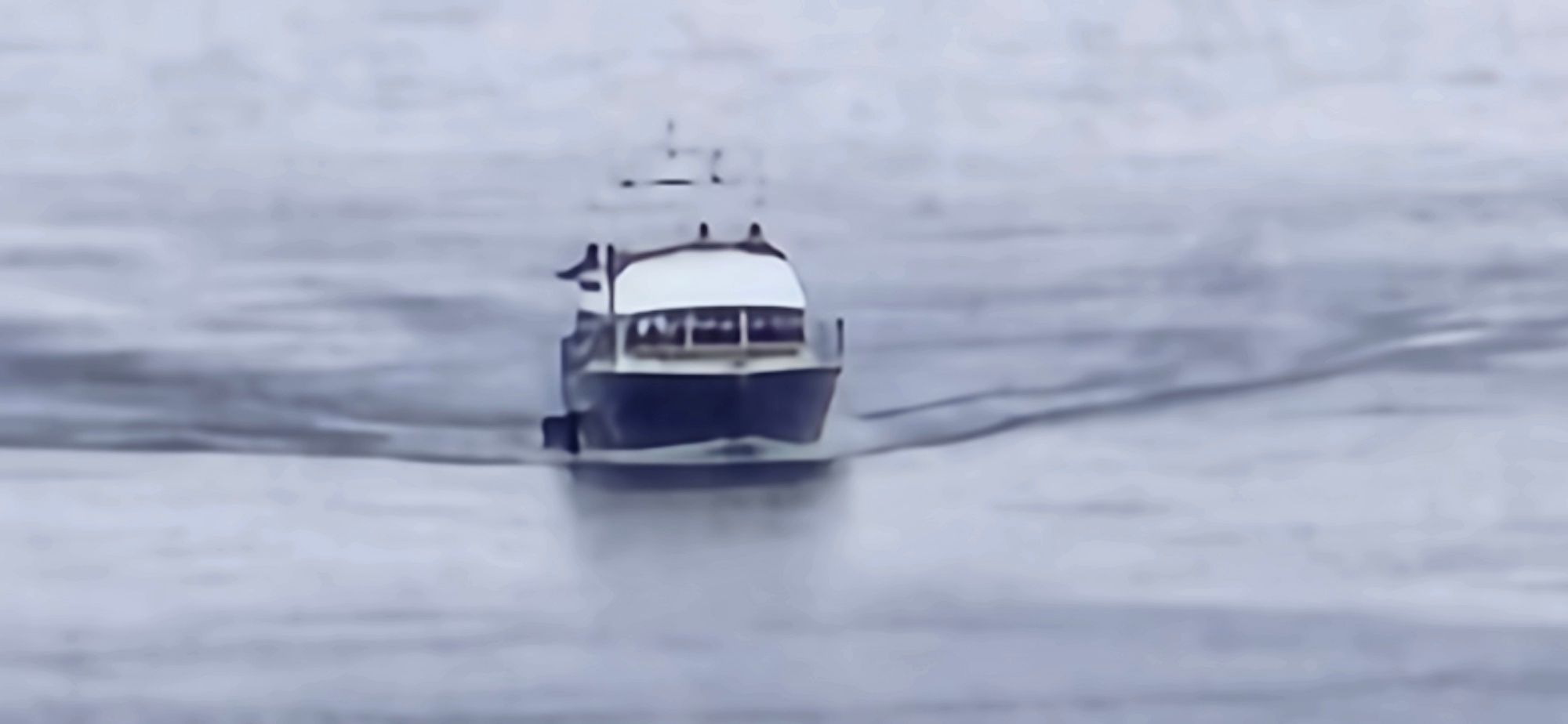 A small blue power boat with a modest wake, moving towards the camera.