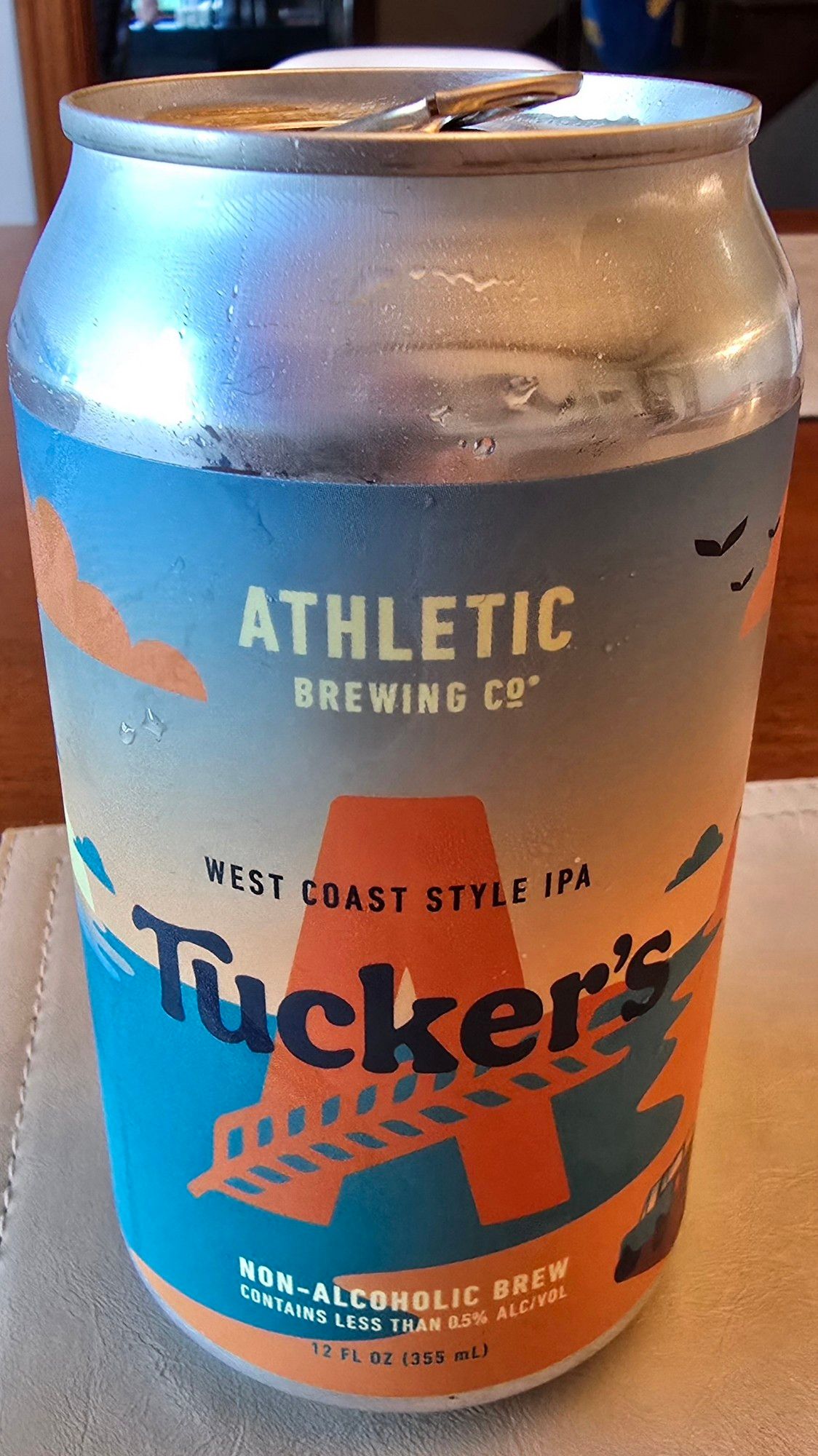 A metal beverage can, with a label reading Athletic Brewing Co, West Coast Style IPA, "Tucker's" non-alcoholic beer.