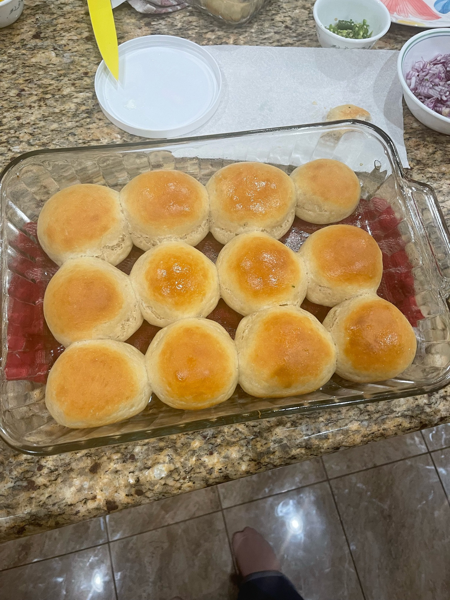 a set of 12 fresh-baked pav rolls, made from scratch in a clear PYREX baking dish, set atop a red towel to protect the counter top. 