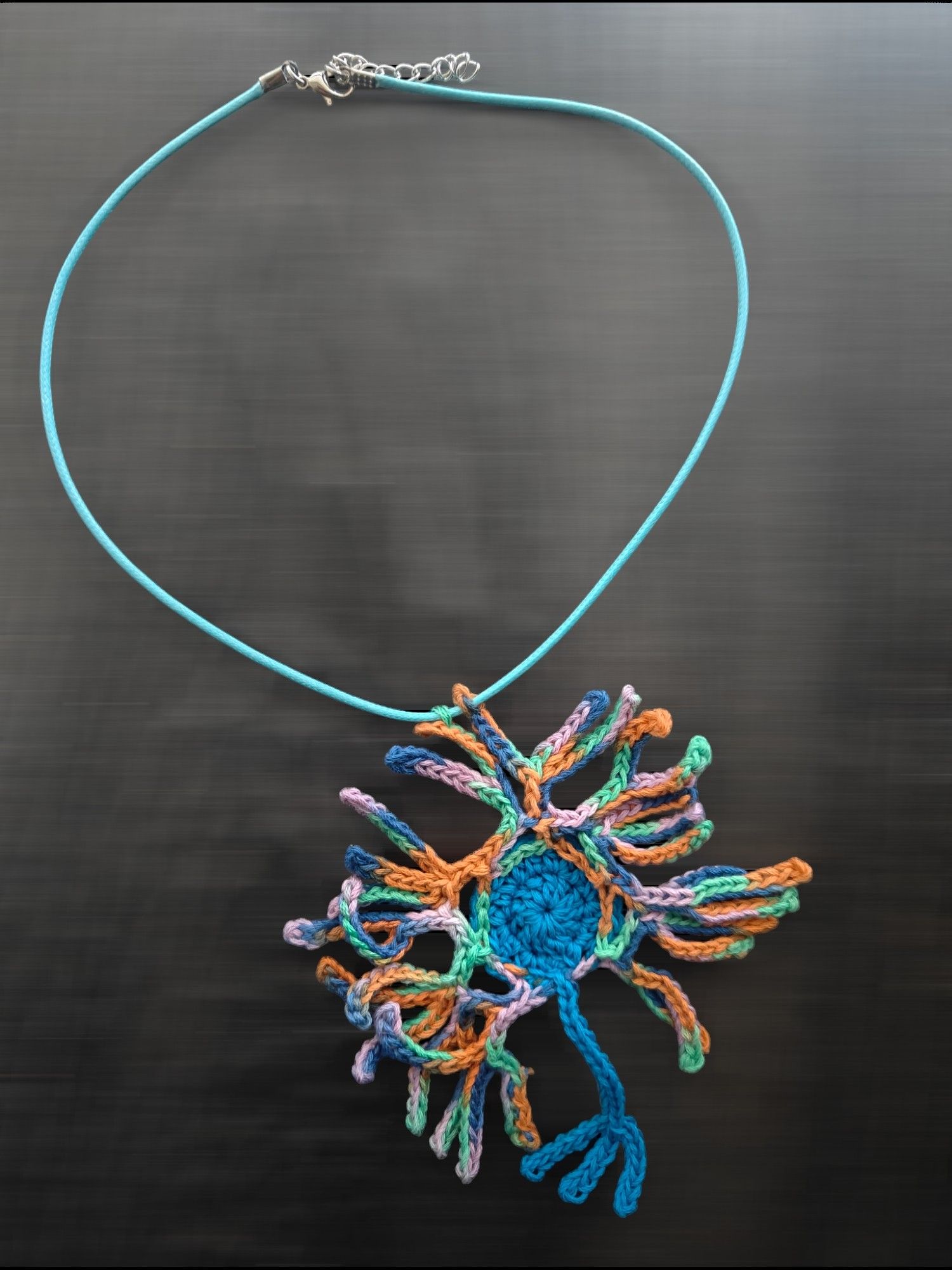 A crocheted neuron necklace.
Cell body and the axon are blue color 
The dendrites are blue and orange