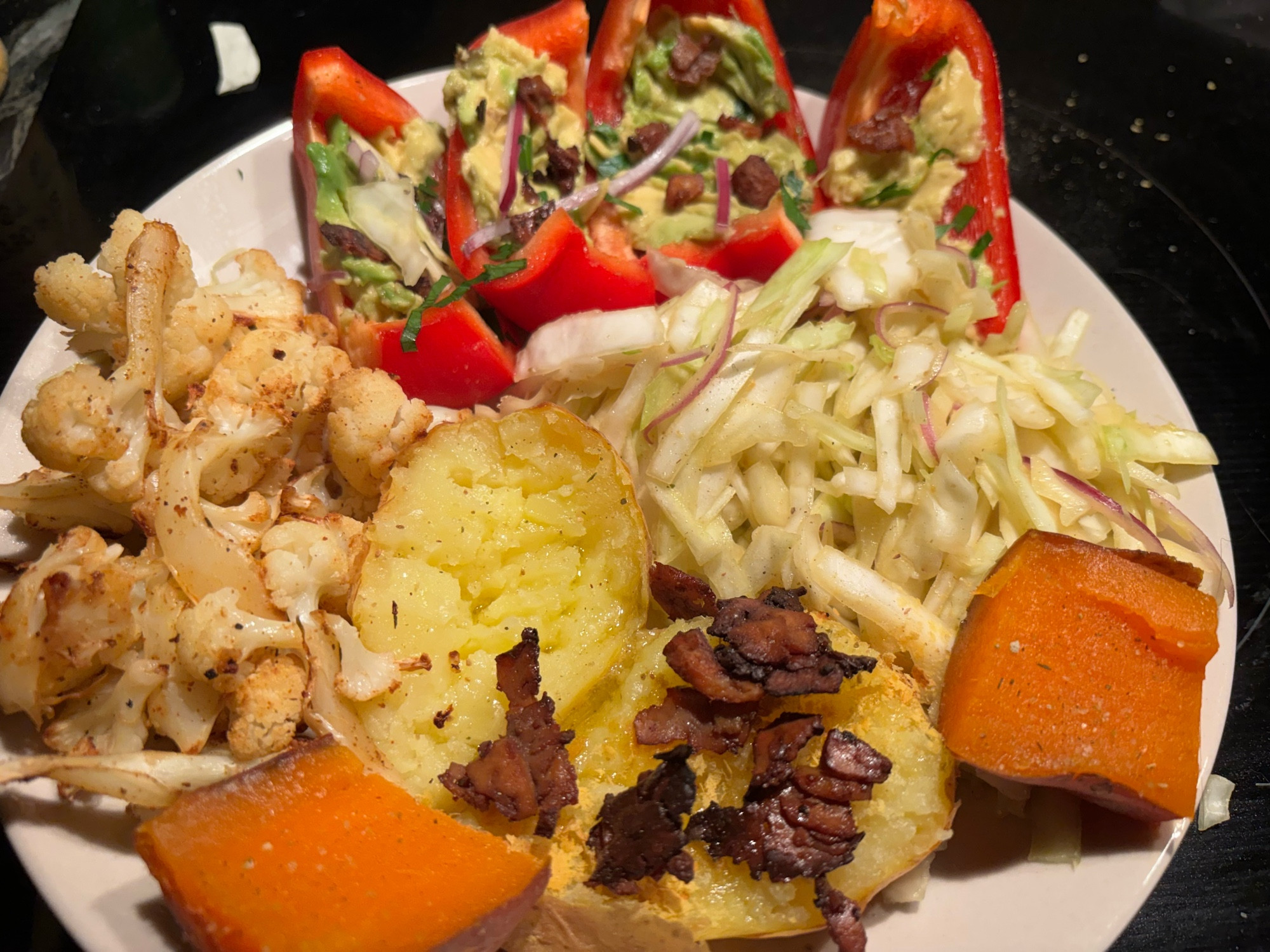 Dinner plate vegan feast: smoked paprika roasted cauliflower, sweet potato chunks, baked potato with tofu ‘bacon’, cabbage slaw and red peppers stuffed with guacamole. Yum!