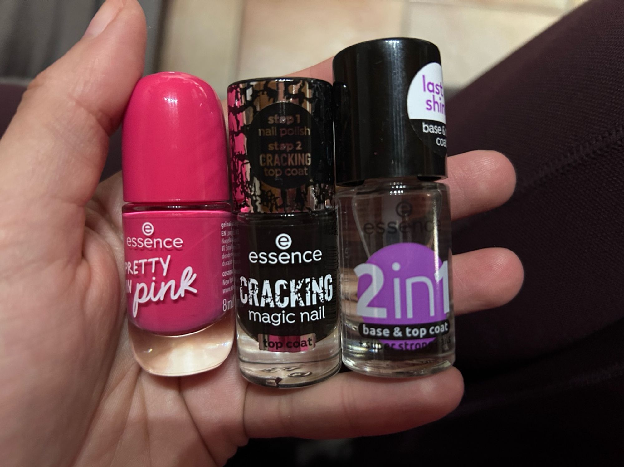 Meine linke Hand hält der Ngellackfläschchen. Von links nach rechts: Pretty in pink - ein pinker Nagellack, crackling magic nail - ein schwarzer Überlack, der beim trocknen aufbricht, 2in1 Klarlack für darunter und drüber