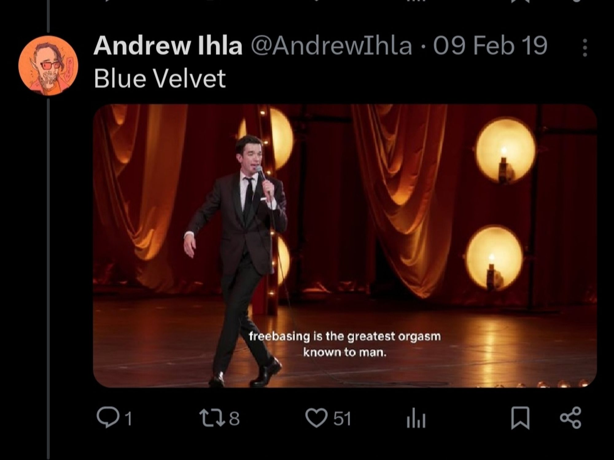 Screenshot of a tweet from the account @andrewihla, featuring a still of John Mulaney saying "freebasing is the greatest orgasm known to man" and the caption "Blue Velvet"