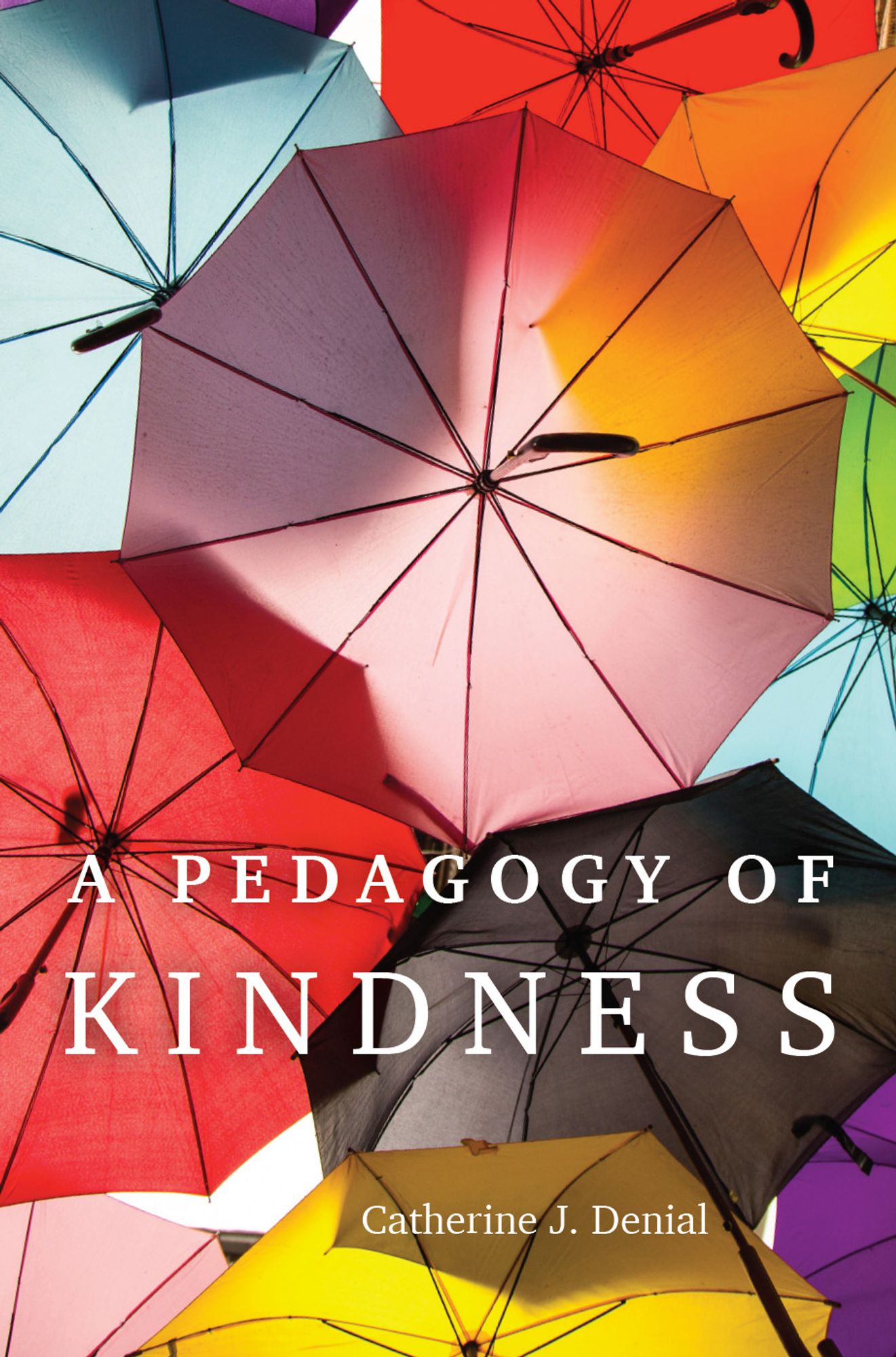 The cover of a book called A Pedagogy of Kindness. Behind the title is a full-page photograph of many different-colored umbrellas open against the sun.