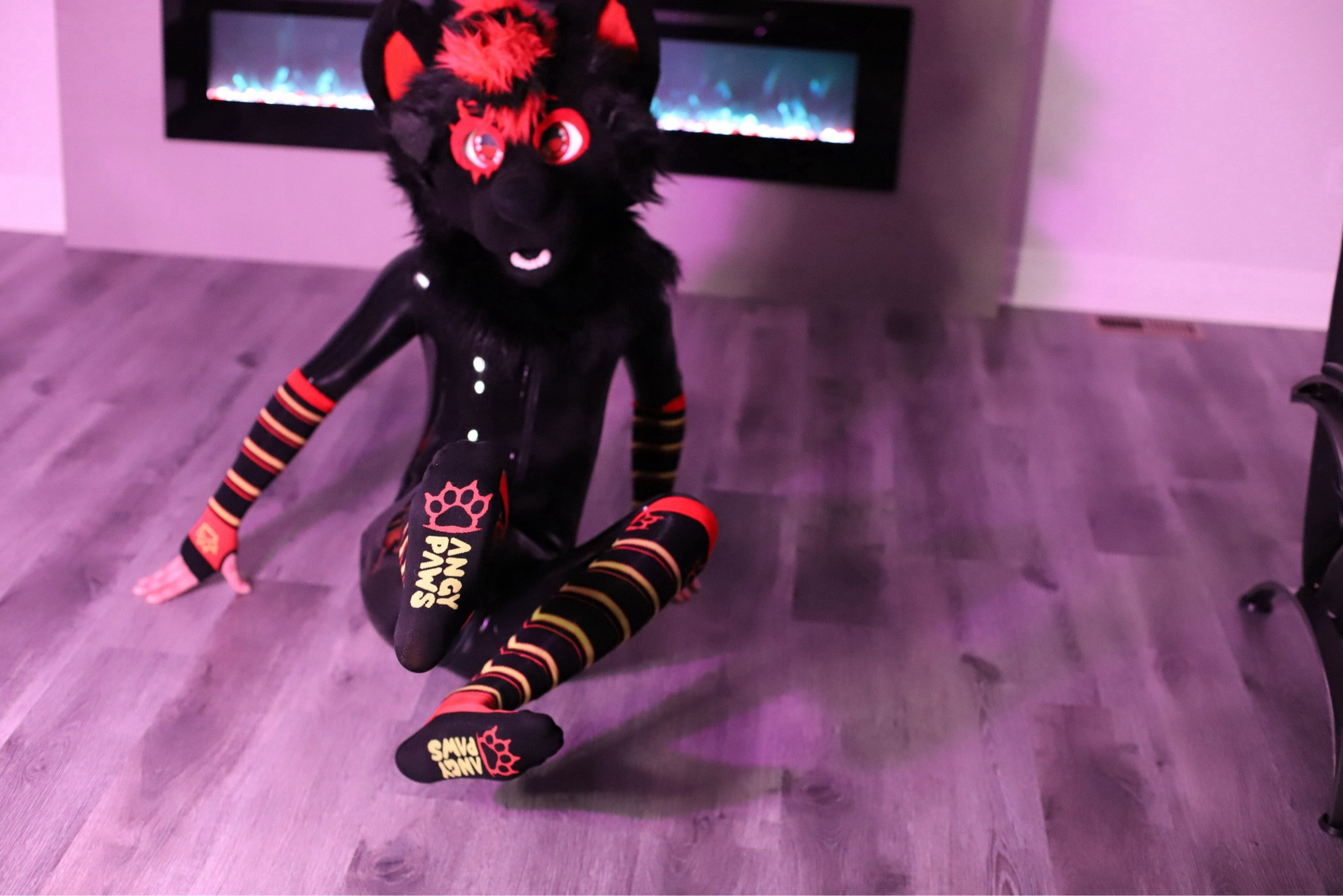 a wolf fursuit wearing latex rubber pride flag colored angy paws socks and arm warmers