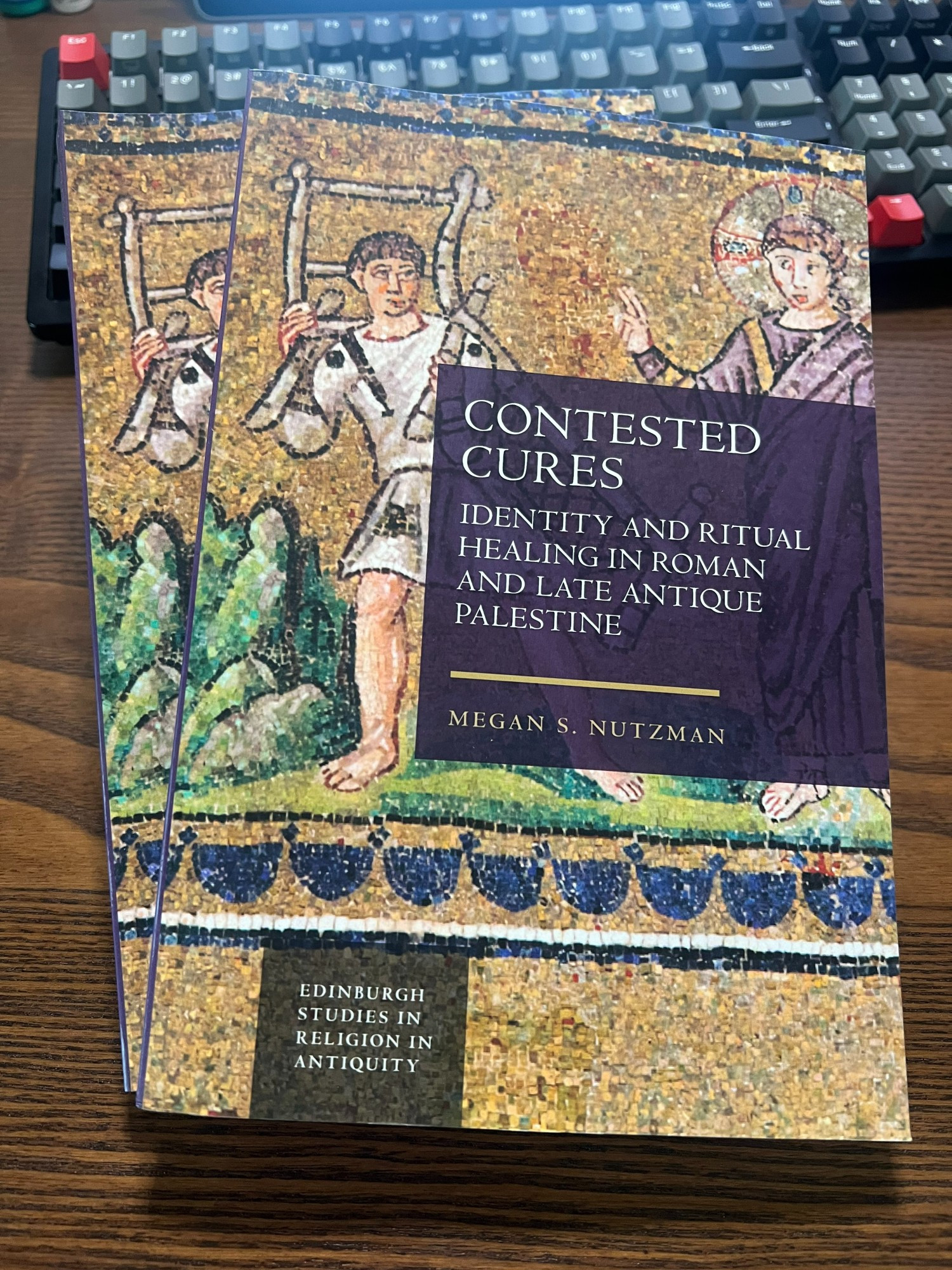 Photograph of two paperback copies of Contested Cures