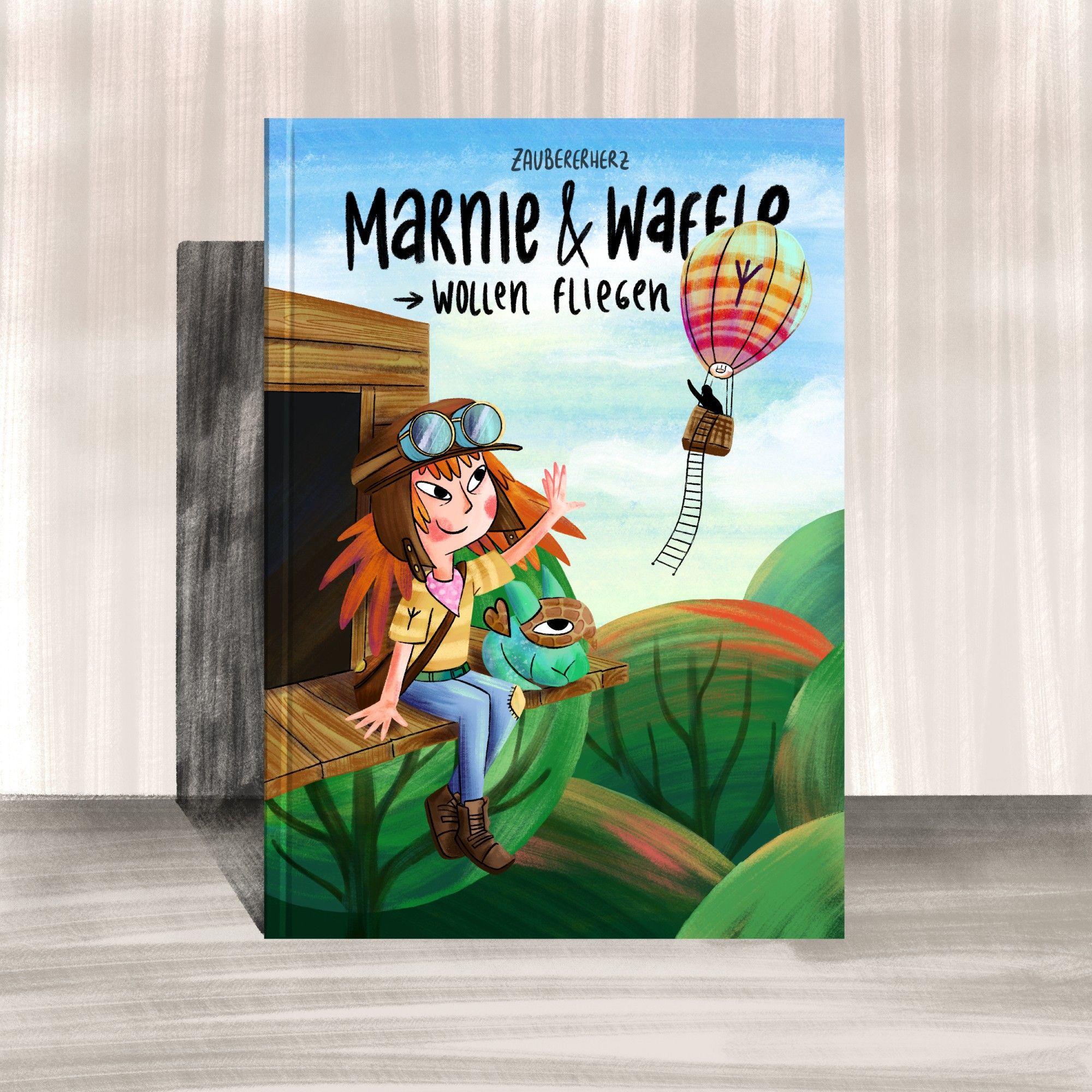 Gezeichnetes Mockup eines Kinderbuchs mit dem Titel "Marnie & Waffle wollen fliegen. Marnie, ein 12 Jähriges Kind, das es liebt Dinge zu erfinden und zu bauen. Sie hat einen imaginären Freund, ein hundeähnlicher Waffeldrachen namens Waffle. Beide sitzen auf einem Baumhaus und winken einem Heißluftballon zu.