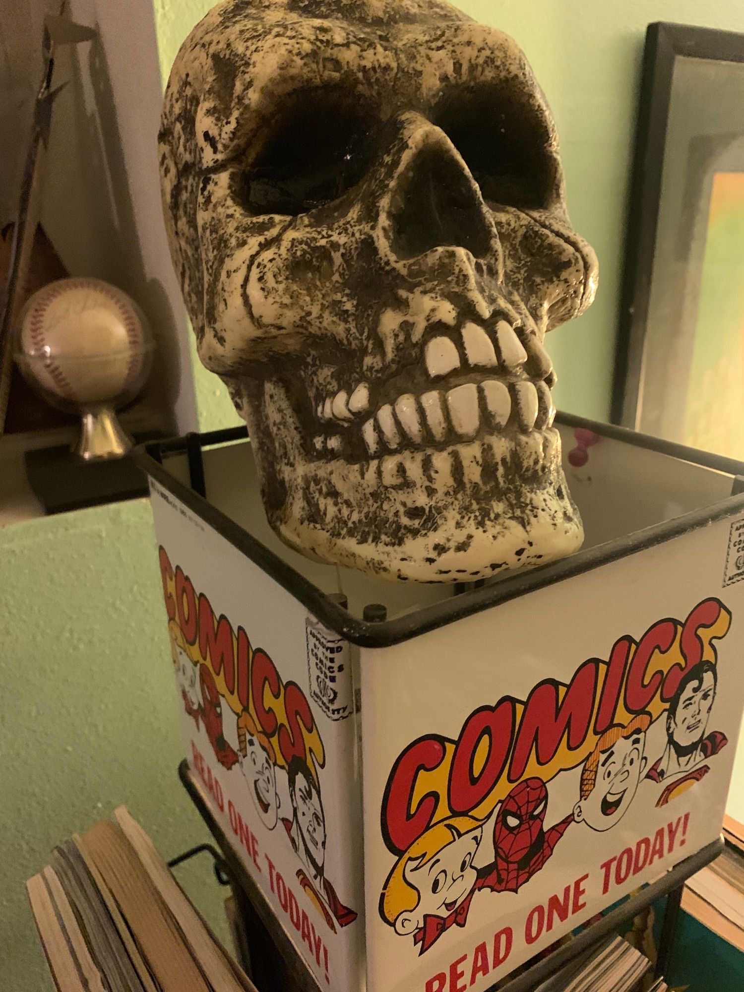 A comic book spinner rack with a plastic skull resting on top