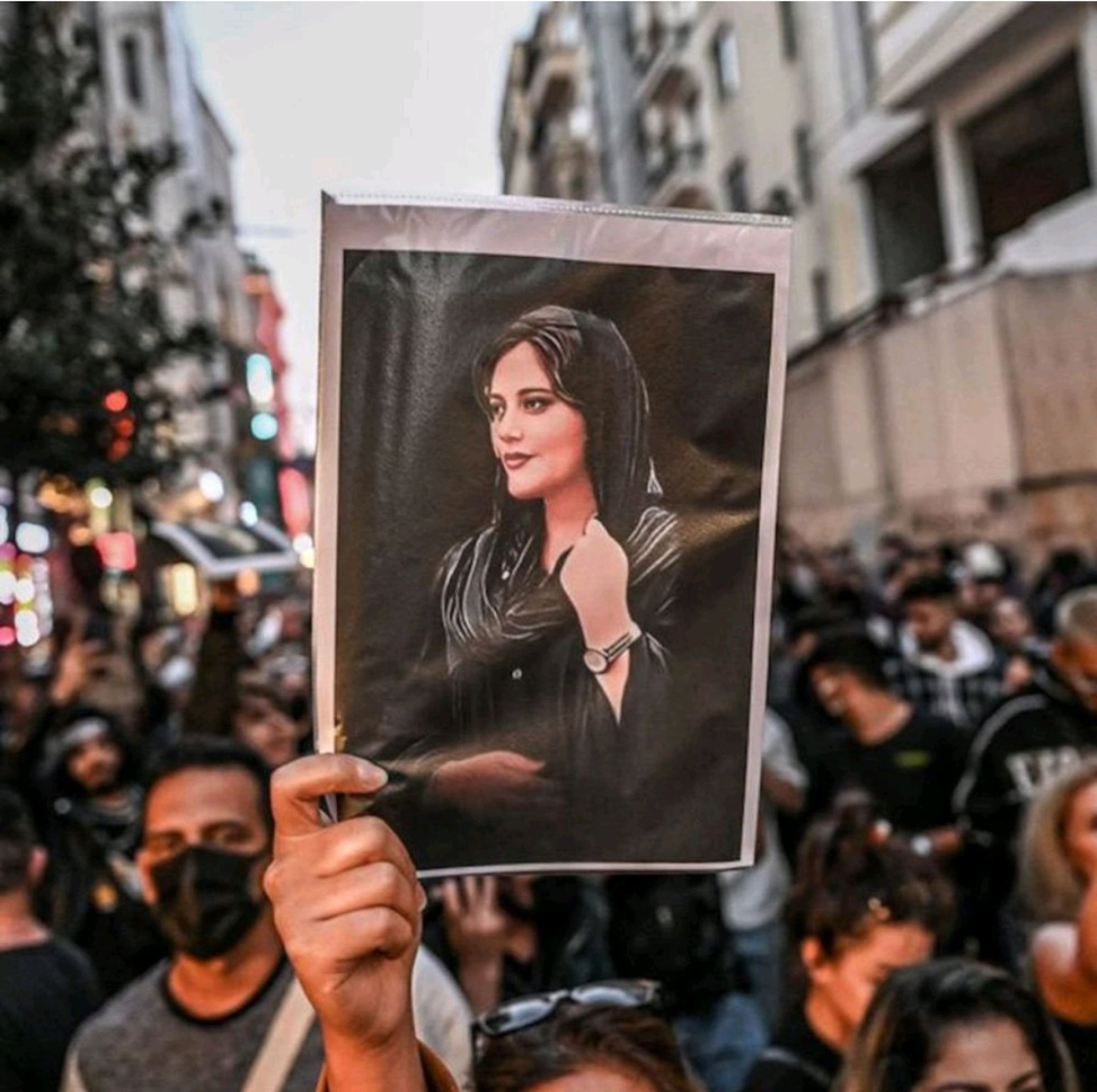 Foto einer Demonstration, bei der ein Bild von JinaMahsaAmini hochgehalten wird.