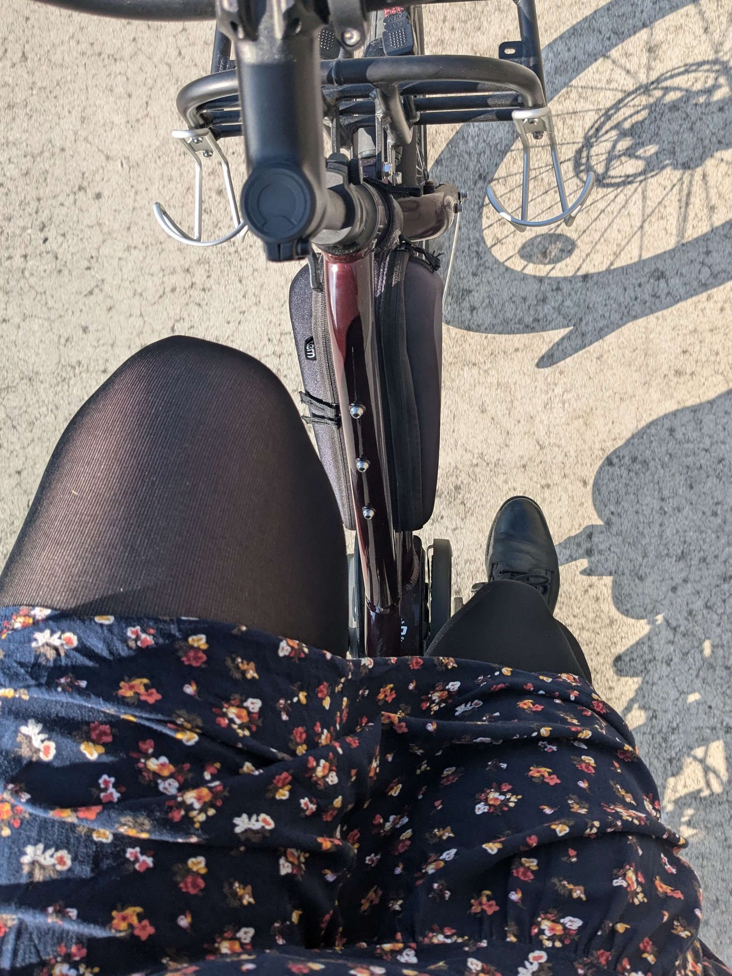 Picture looking down on my legs while riding a bike. I'm wearing a floral dress, black tights, and black lace-up boots.