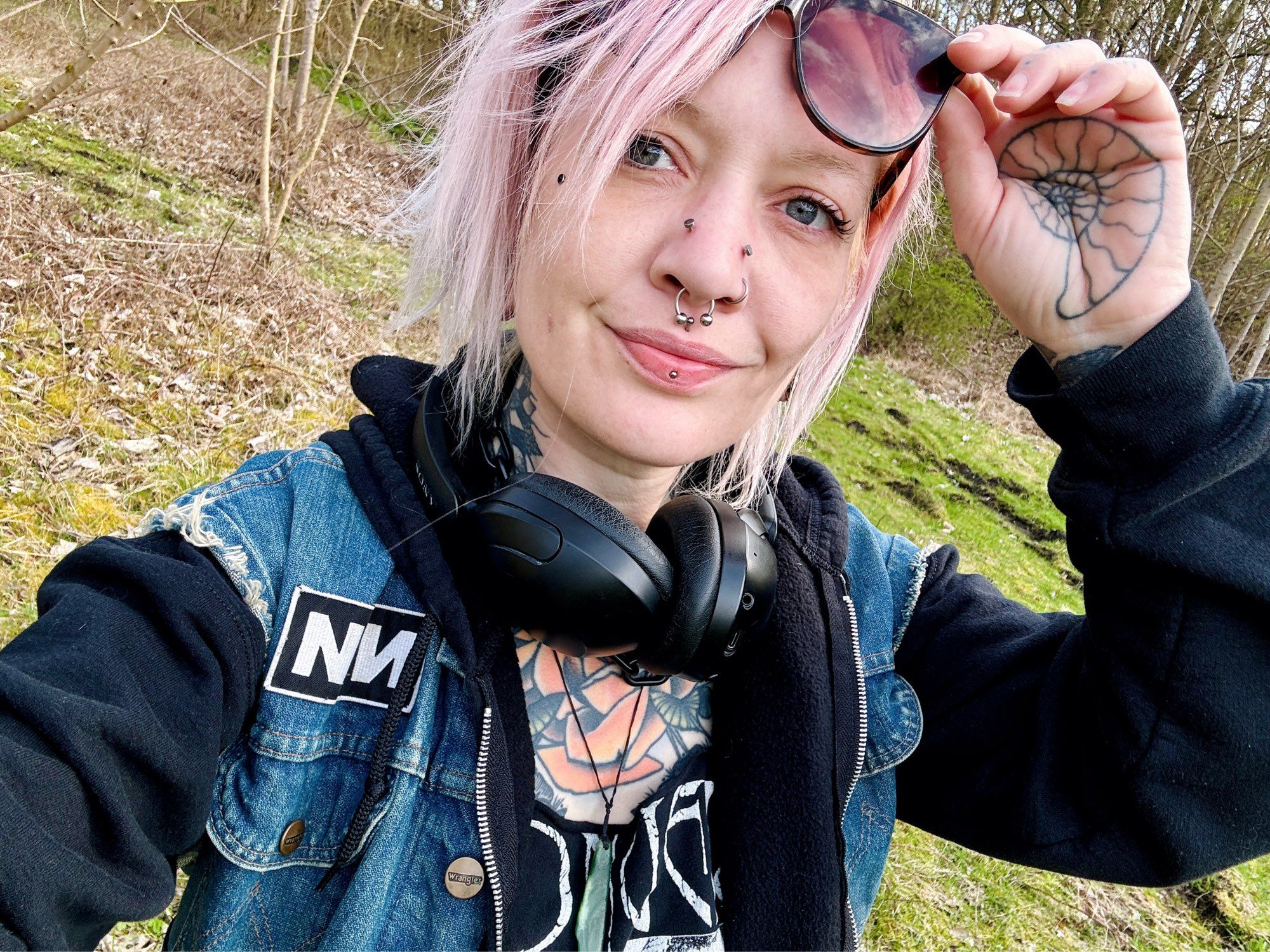 Selfie of Katie taken in an old quarry. She’s lifting a pair of sunglasses off her head and you can see new high nostril piercings. Her nose is super swollen, especially the right side (left in photo) which has swollen way more and looks ridiculous haha.