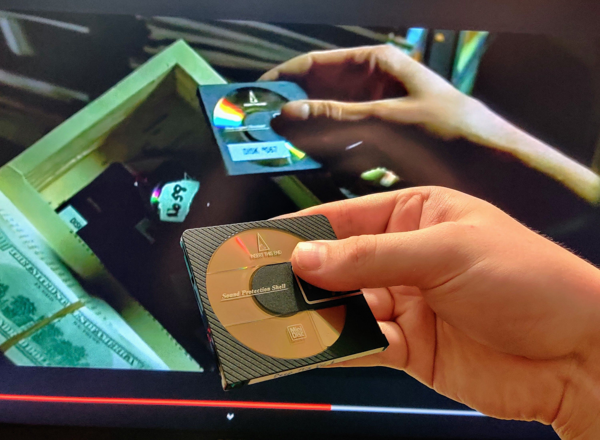 screenshot of the matrix showing neo pulling a minidisc containing what is likely malware out of a hollowed out book to give to a skeevy white dude