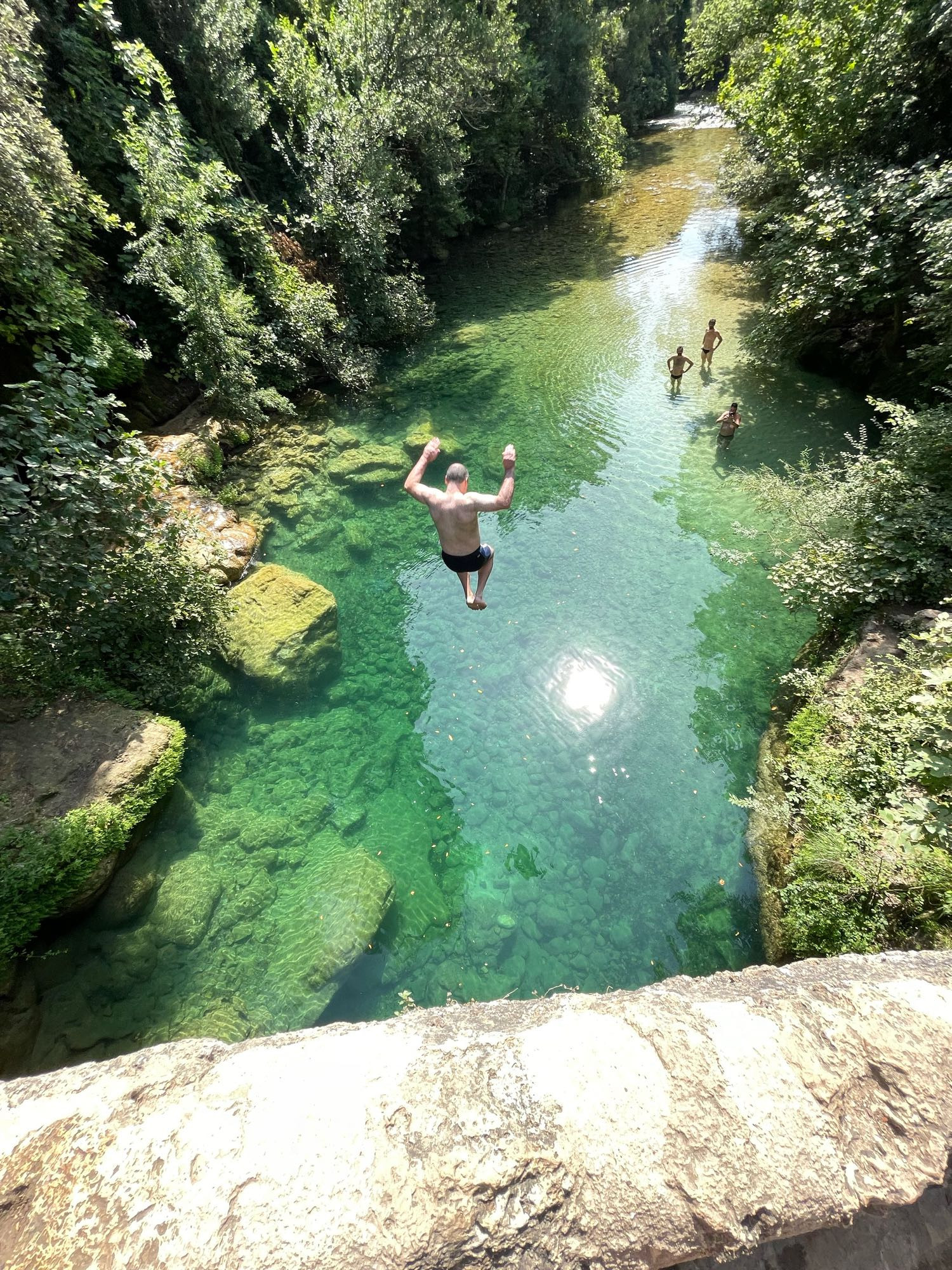 un homme saute dans l’eau turquoise des gorges de la siagne