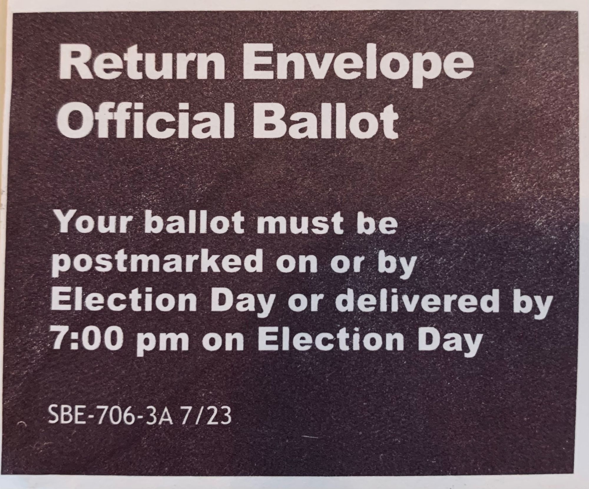 Against a dark backdrop are the words (in white) “Return Envelope Official Ballot: Your ballot must be postmarked on or by Election Day or delivered by 7:00pm on Election Day.” 