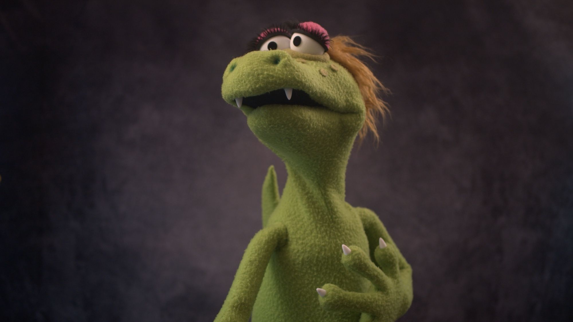 Right view of a green alligator puppet with blonde hair and large eyelashes