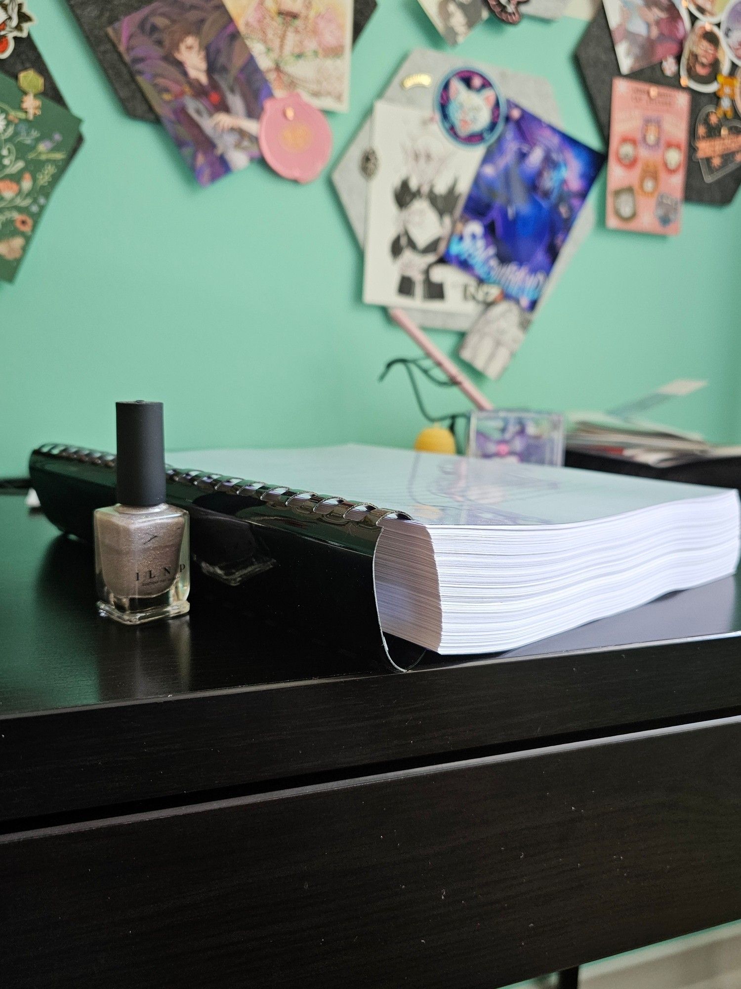 the same manuscript viewed from the side, showing that it's about 1,5 inch thick. it is a little thicker than the glass part of the bottle of nail polish that has been put next to it for comparison.