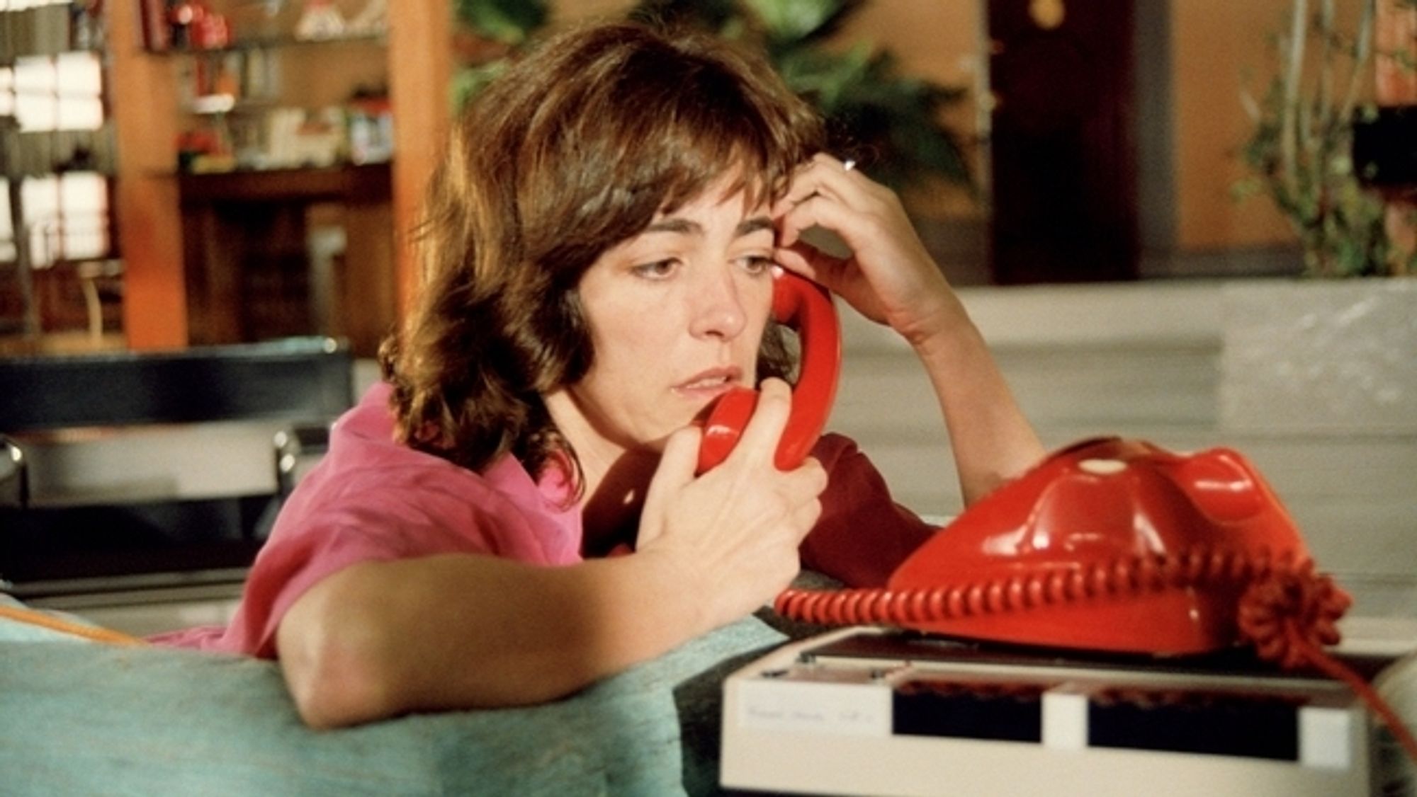 A worried looking woman talking into a very red phone the colors in that film are amazing