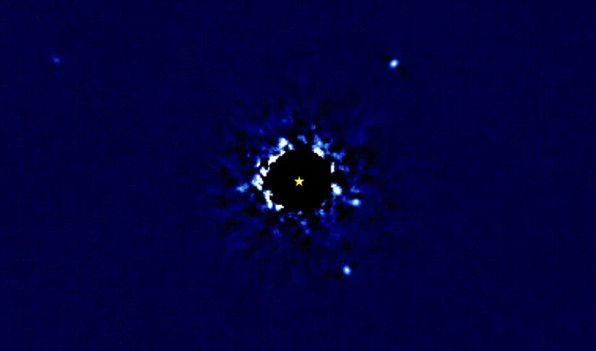 Blue field with a black circle in the center and a little yellow star icon in the center of that. Four small white dots surround the black circle, as well as noise from the star itself.