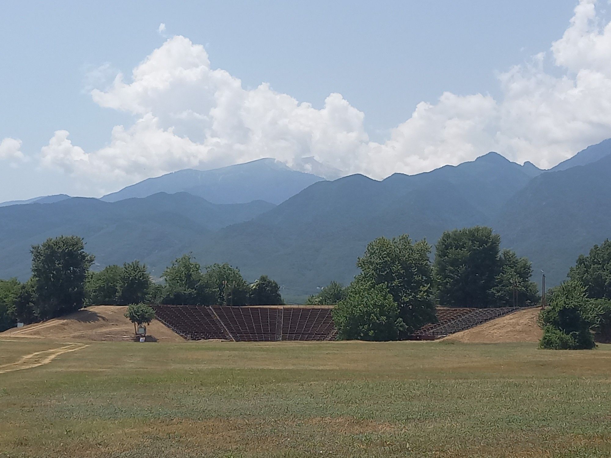 Distant view of an ancient theatre with modern wooden seating (Hellenistic theatre of Dion), against a background of mountains (Mt Olympus).