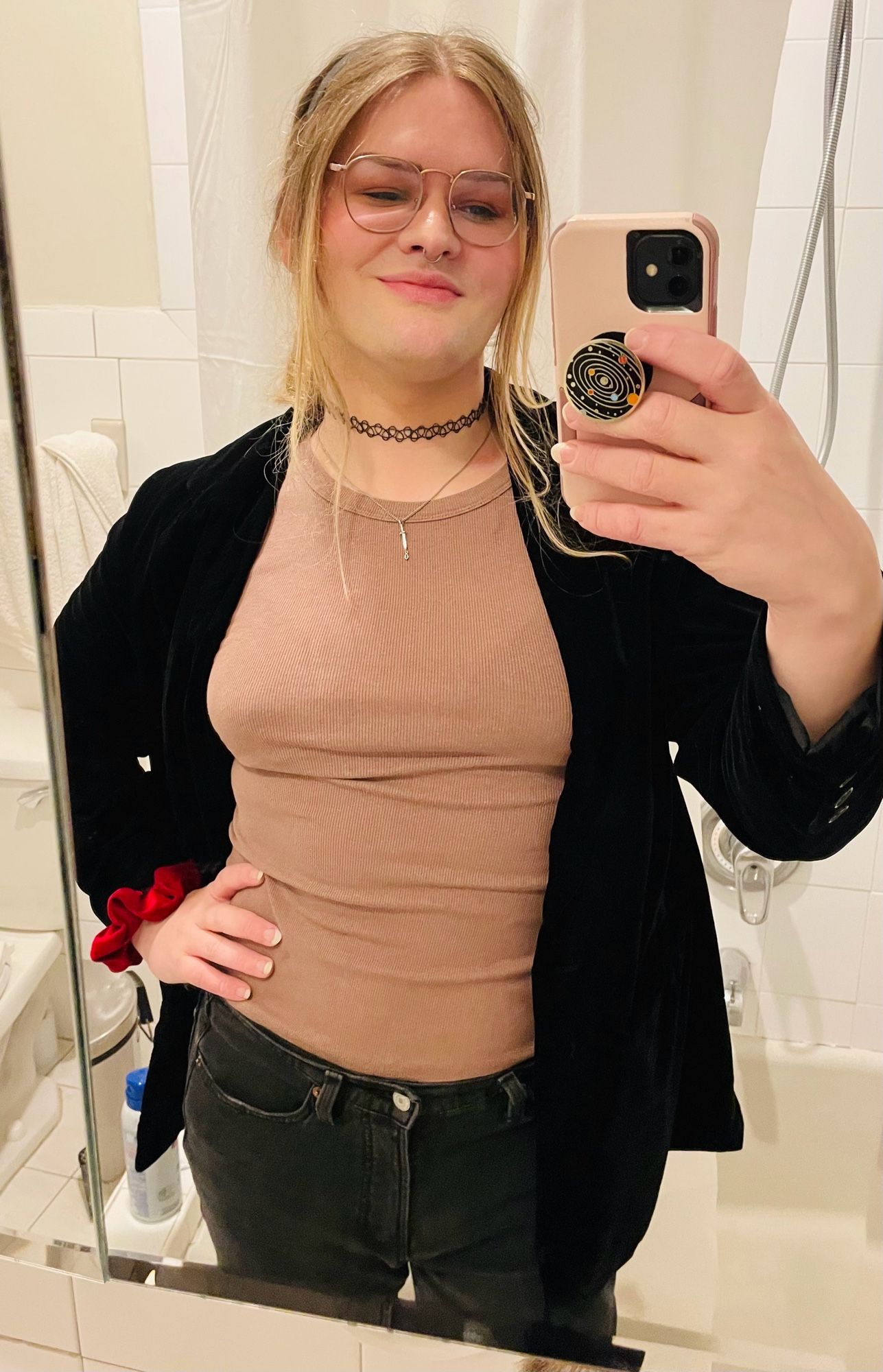 willow mirror selfie. she's wearing an oversized black sateen jacket over a light brown tank top with faded black jeans