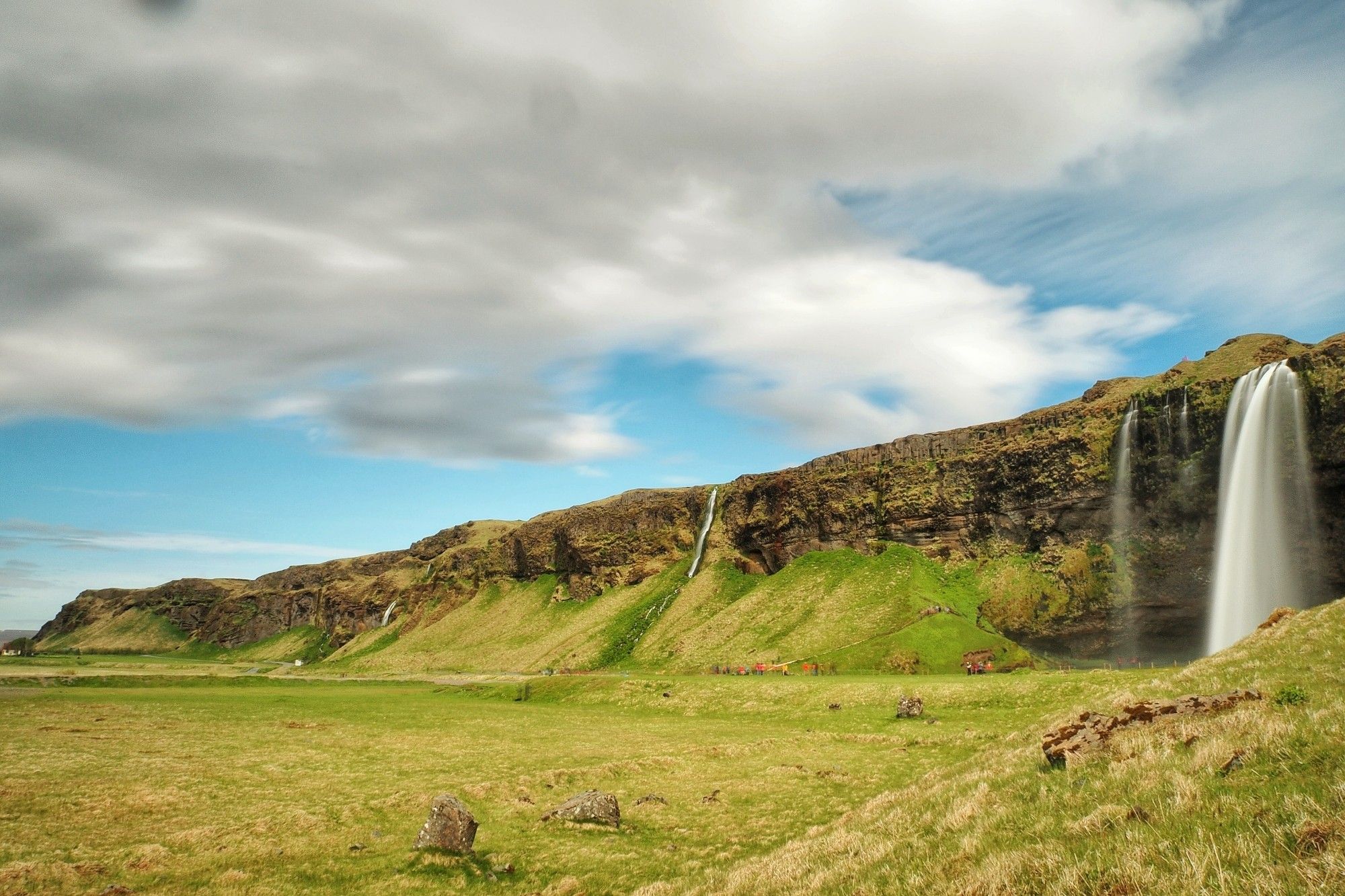 grüne Landschaft, ein Wasserfall, und Wolken mit eine wenig blauem Himmel. Langzeitbelichtung