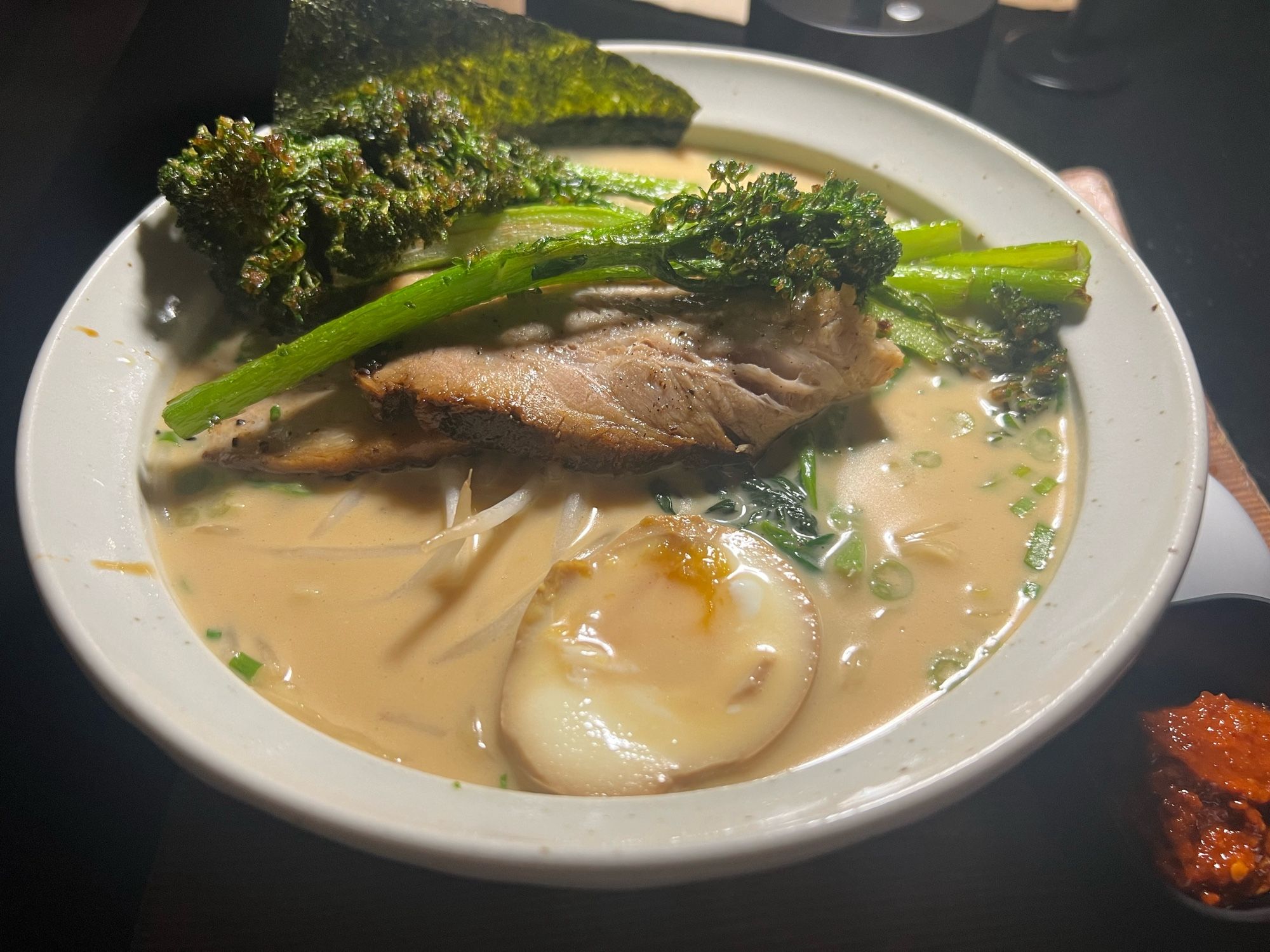 a bowl of tonkotsu ramen with some broiled broccolini on top