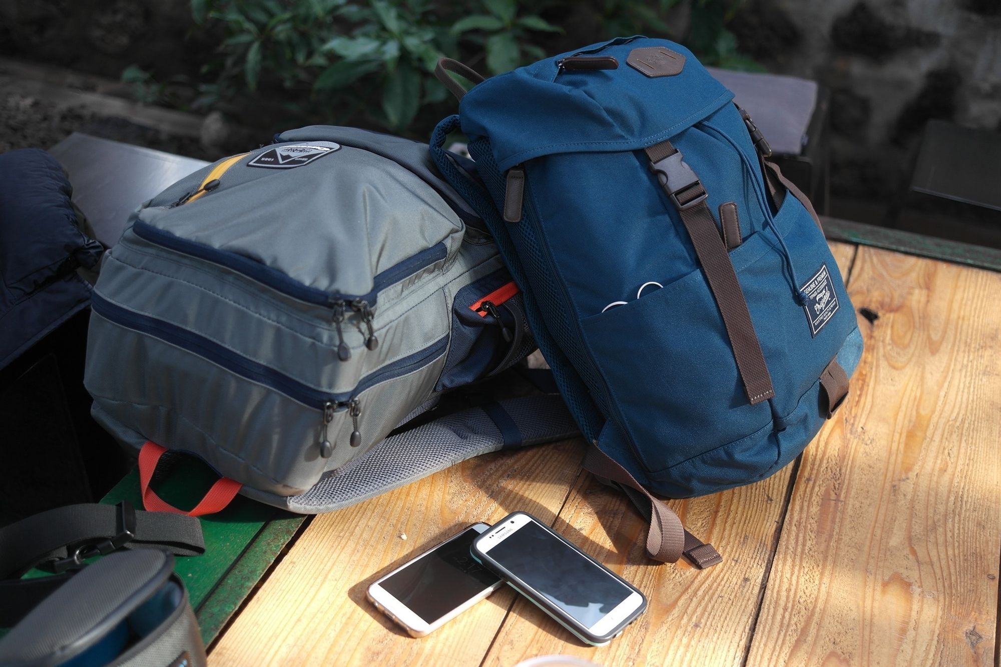 duas mochilas de viagem sobre uma mesa com dois celulares sobrepostos