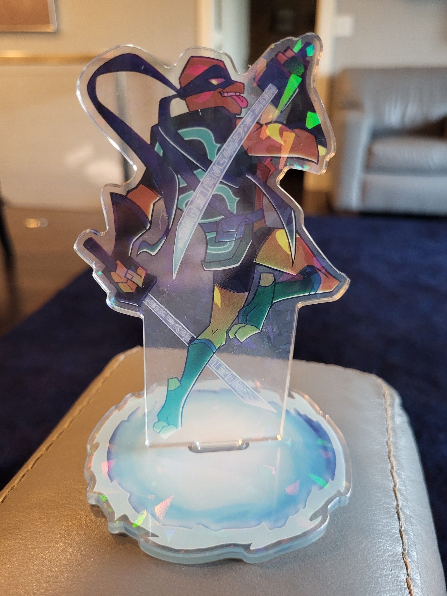 a holographic standee of Leonardo from Rise of the TMNT. his back is turned as he peers over his shoulder and sticks his tongue out. in each hand he holds a katana. the base of the standee is made to look like one of his portals.