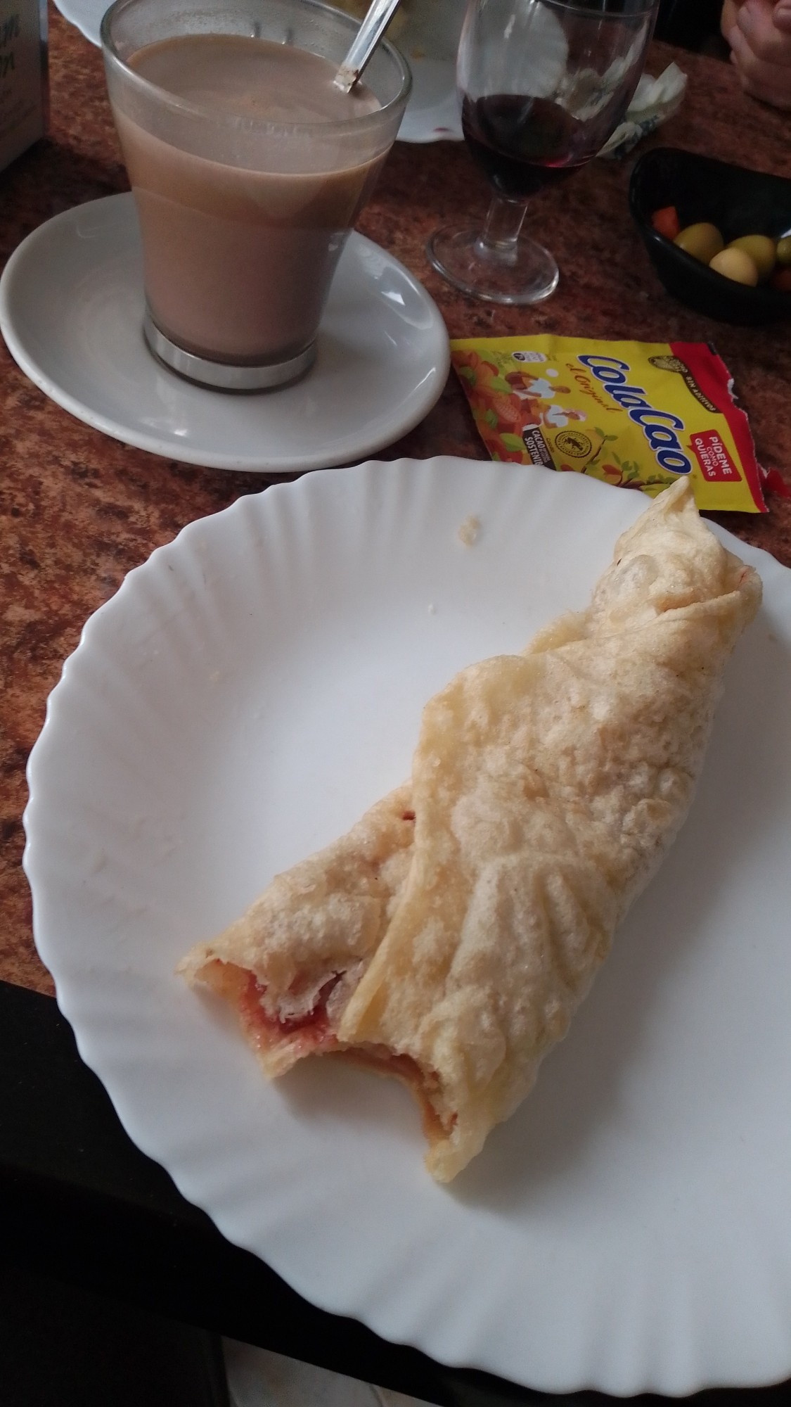 Una torta frita y un cola cao en un bar.